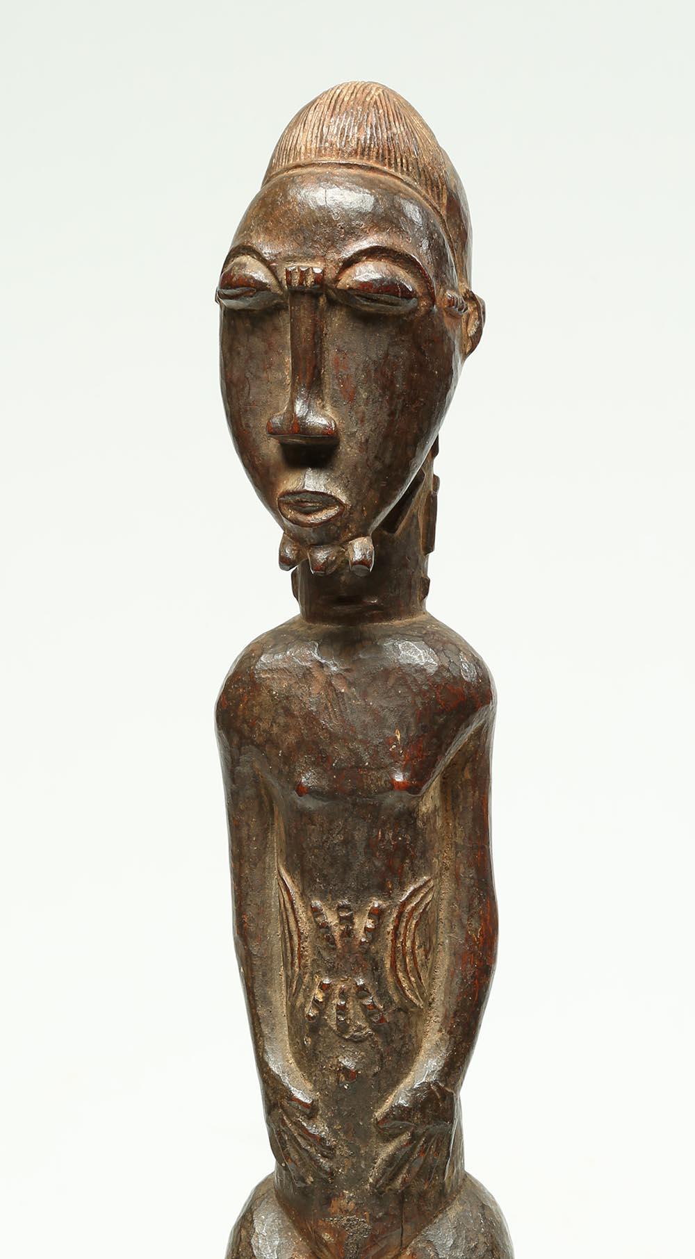 Wood Tribal Baule standing male figure, important provenance

Early Baule standing male figure with hands on stomach, three pronged beard, finely carved hair style. Elaborate carved raised scarification marks on body. Old stabile crack in base and