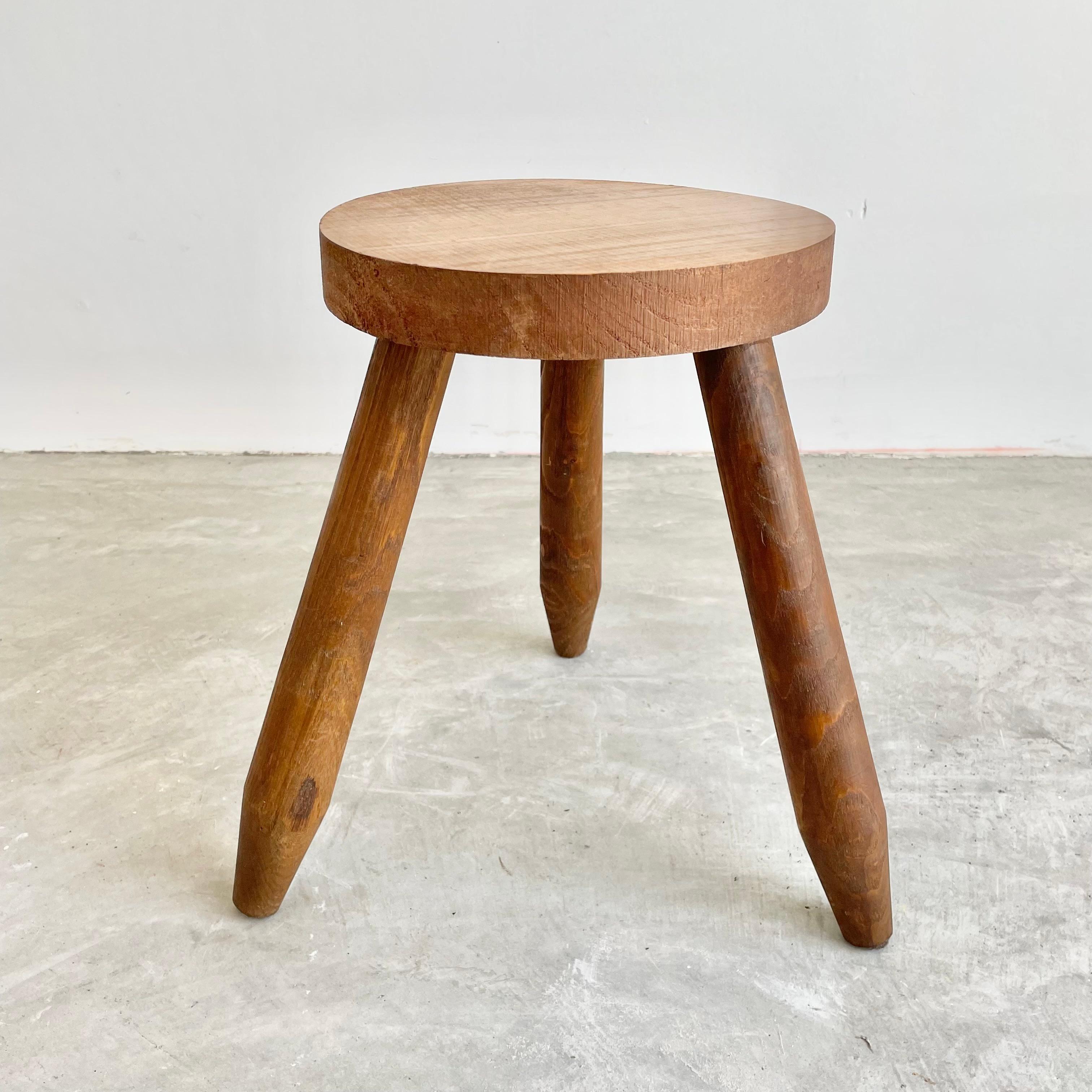 Minimalist wooden tripod stool made in France, circa 1960s. Substantial and chunky, this stool has 3 club legs that screw into base. Raw grain to the wood which gives the piece nice patina and color. Perfect for books or objects.
      