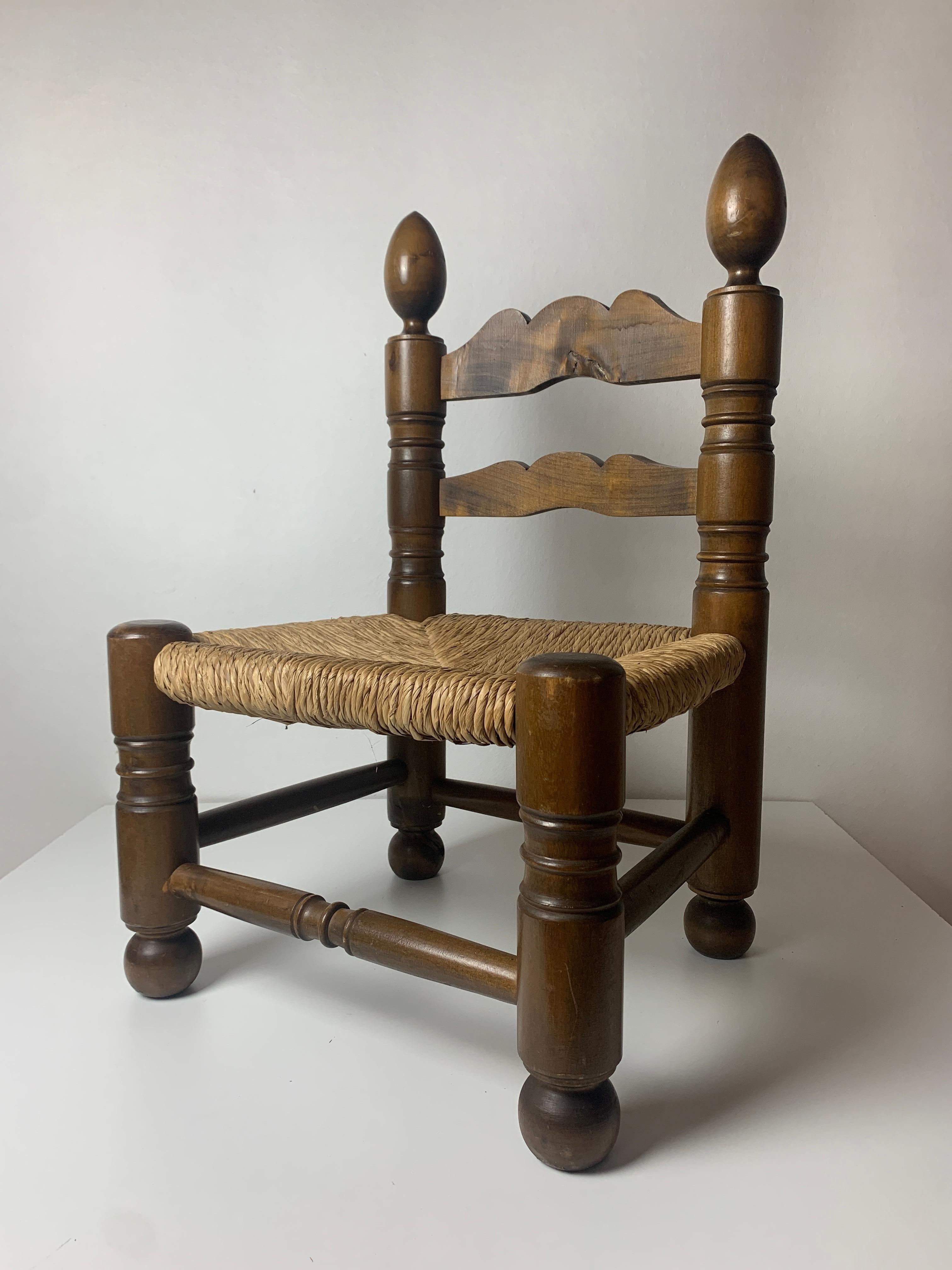 Superbe chaise basse en jonc, souvent nommée dans le style de Charles Dudouyt, avec de jolis pieds en forme de sphère ou de boule et deux grands fleurons en forme de glands au sommet du dossier. Cette magnifique petite chaise peut être utilisée