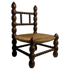 Brutalist wood turned bobbin low rush chair in the style of Charles Dudouyt