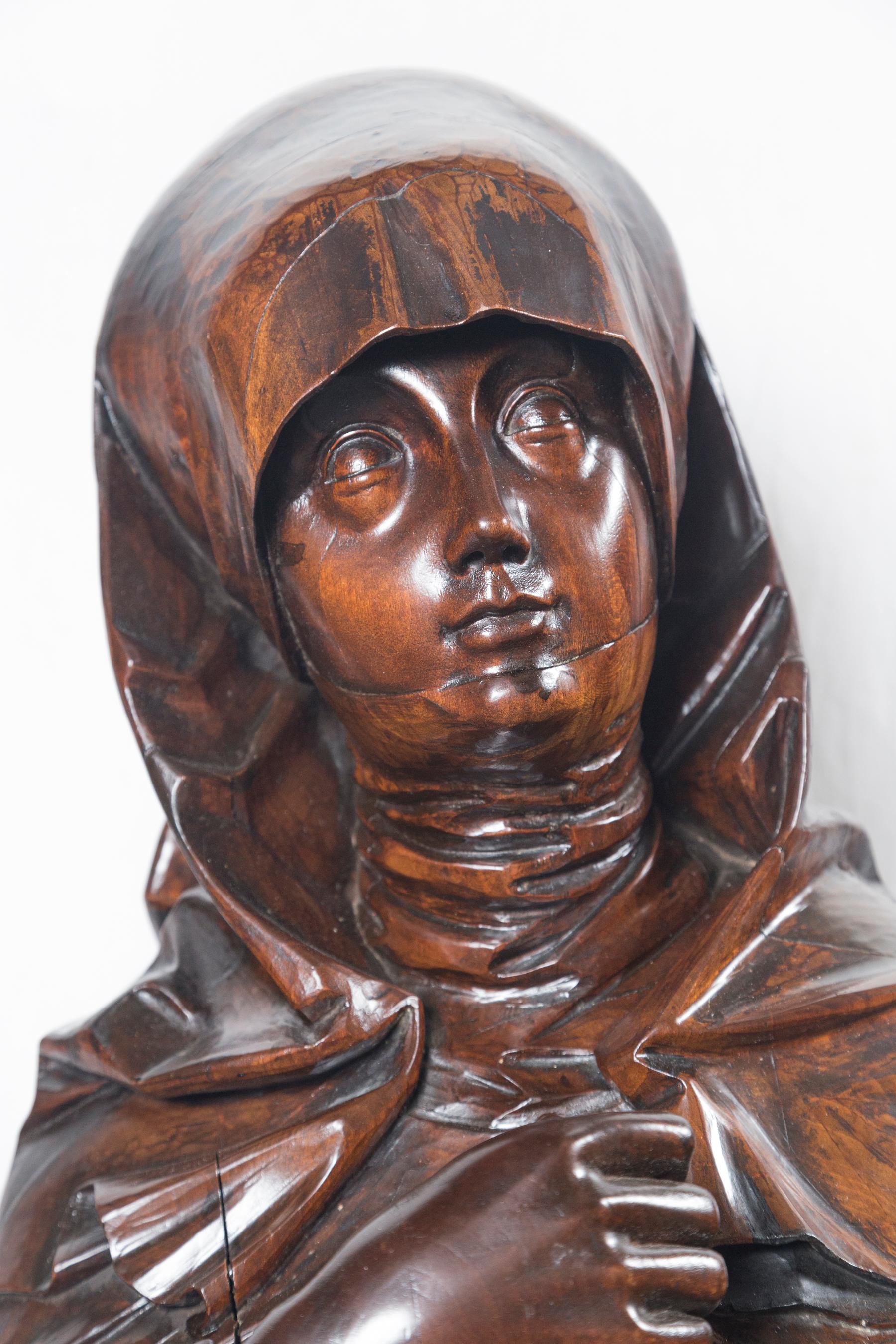 Made of solid wood, likely walnut. She wears a long garment and head covering. Her eyes, looking upward to the heavens. Her hands clutched at her chest.
The octangle base is approx. 2 inches tall.