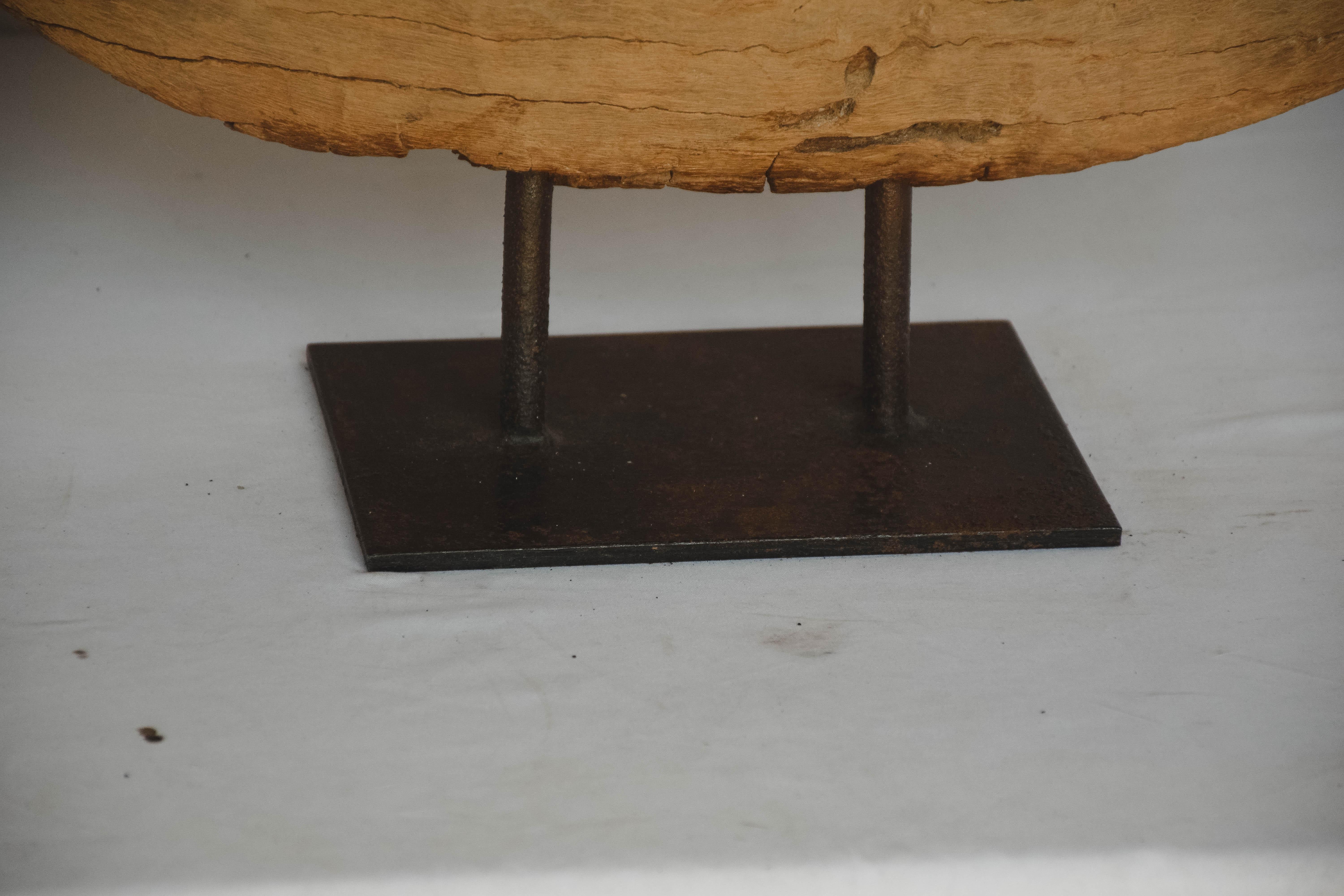 Vintage rustic wood wheel from a wooden cart mounted on an iron stand. This large hand carved wooden wheel shows natural age splits and texture and will serve as a wonderful piece of art.