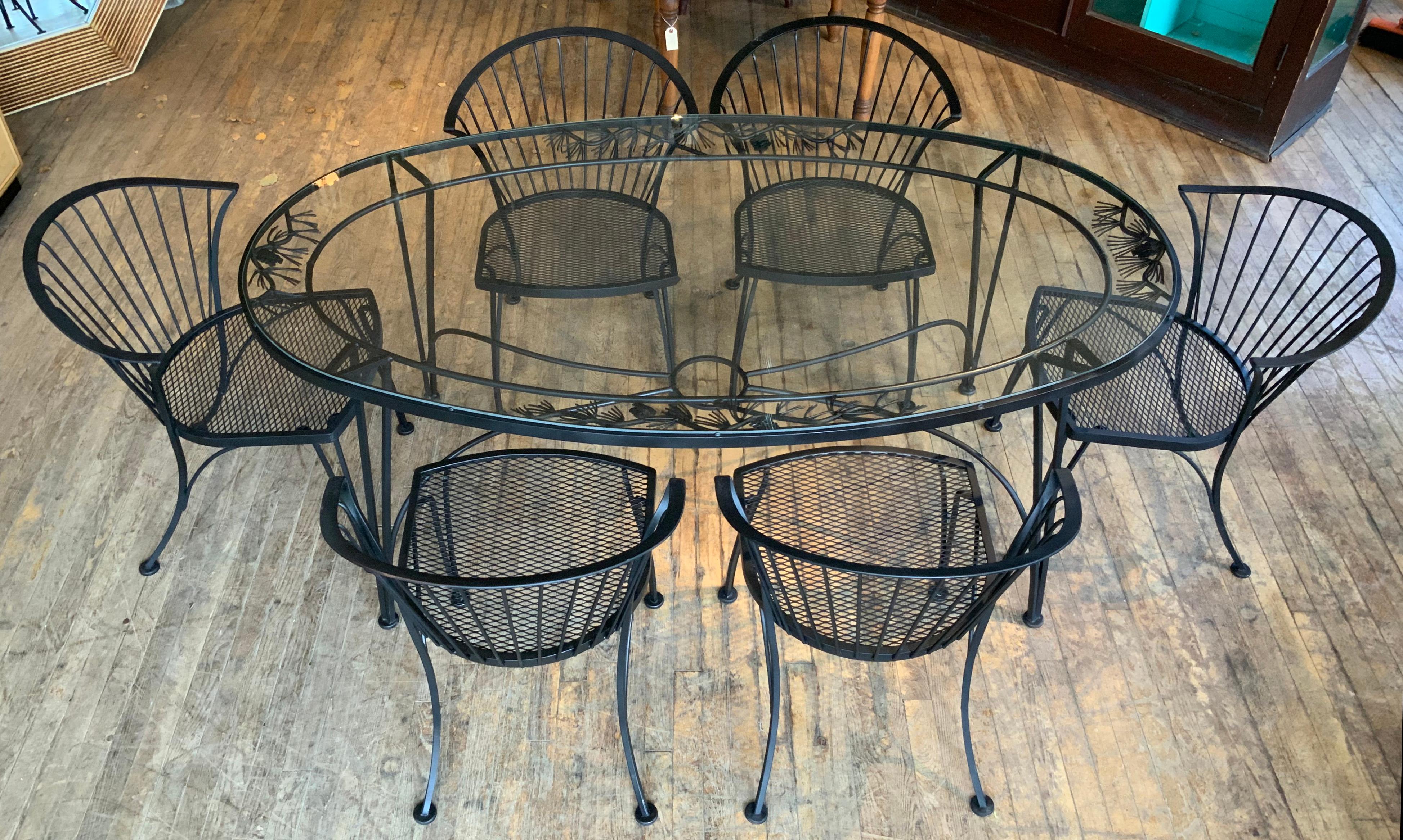 A vintage 1950s wrought iron garden dining set by Woodard. 'Pinecrest' was one of their most charming designs in the 1950s, named for the pine needle & pinecone motif in the skirt of the dining table. this set consists of the large oval dining