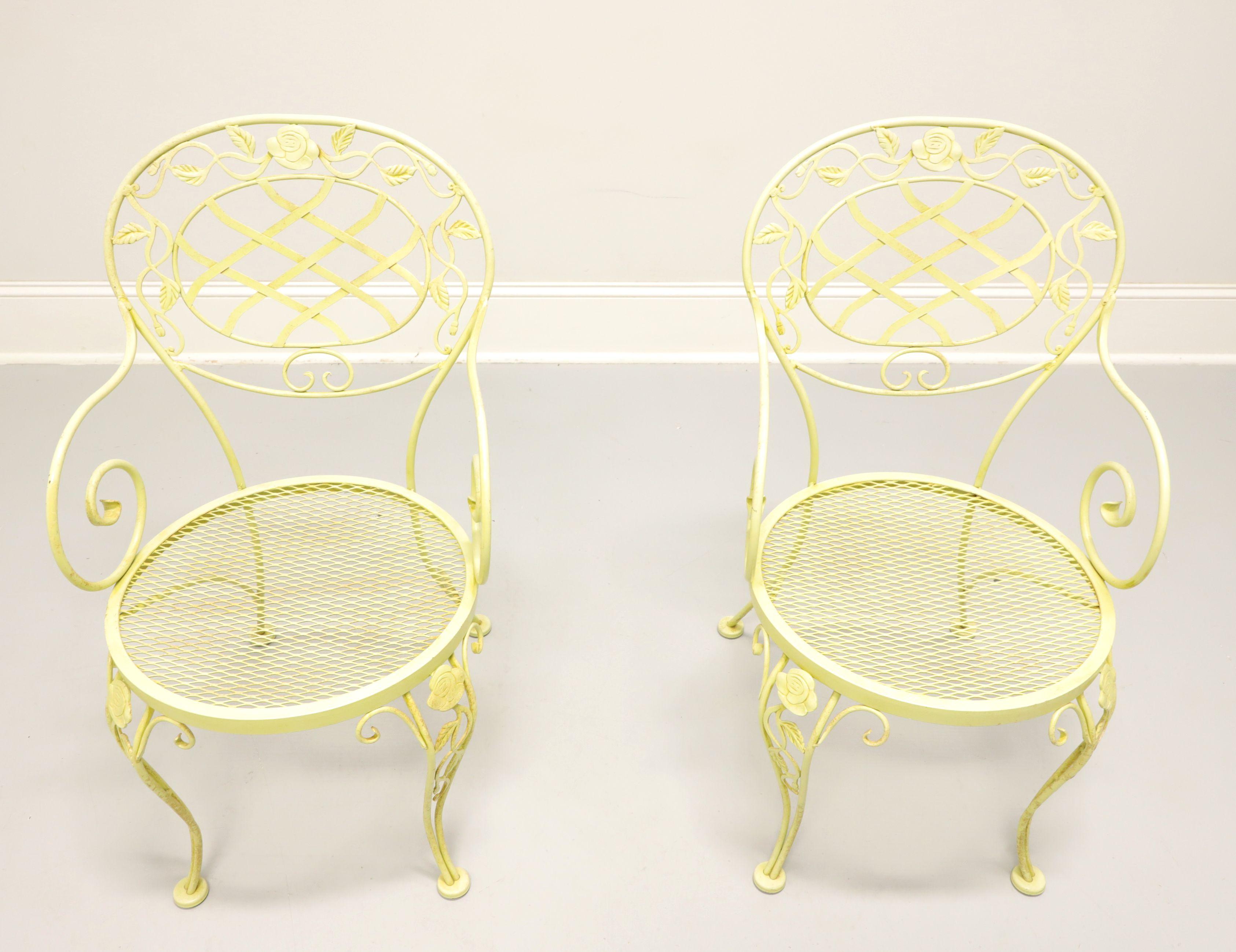 A pair of Mid 20th Century wrought iron patio armchairs in the Regency style by Woodard Furniture, their Chantilly Rose. Wrought iron metal frame, yellow painted finish, rounded back with lattice design center, roses & leaves adornments, rounded