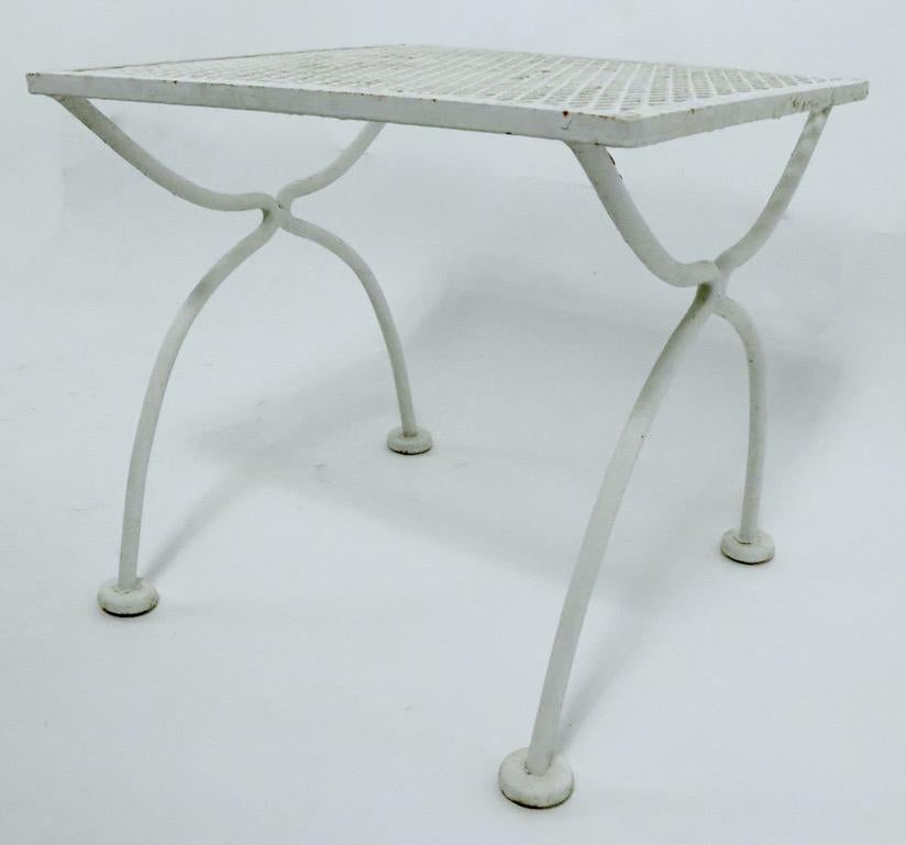 Diminutive side, patio, garden table by Woodard Furniture Company. The table has a metal mesh top, and wrought iron legs. Currently in old white paint finish, we also offer powder coating if you want a more polished look.