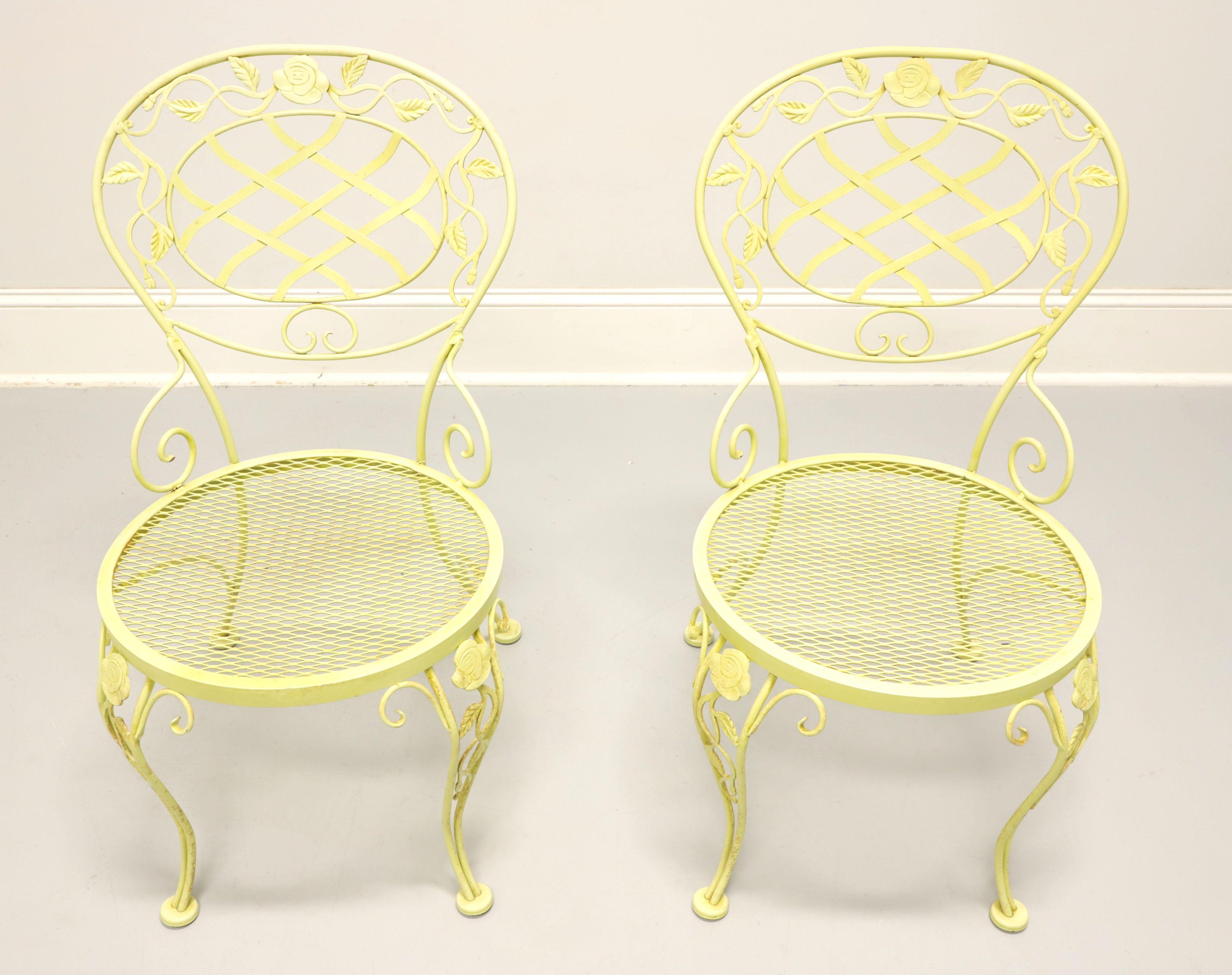 A pair of Mid 20th Century wrought iron patio side chairs in the Regency style by Woodard Furniture, their Chantilly Rose. Wrought iron metal frame, yellow painted finish, rounded back with lattice design center, roses & leaves adornments, mesh