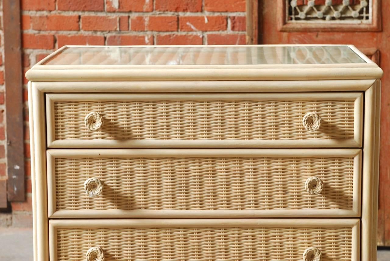 Whitecraft for Woodard Furniture Company chest of drawers or commode. Constructed from woven wicker and split rattan with a light painted finish. The case is covered by wicker and framed with rattan. The top has a piece of fitted glass and is
