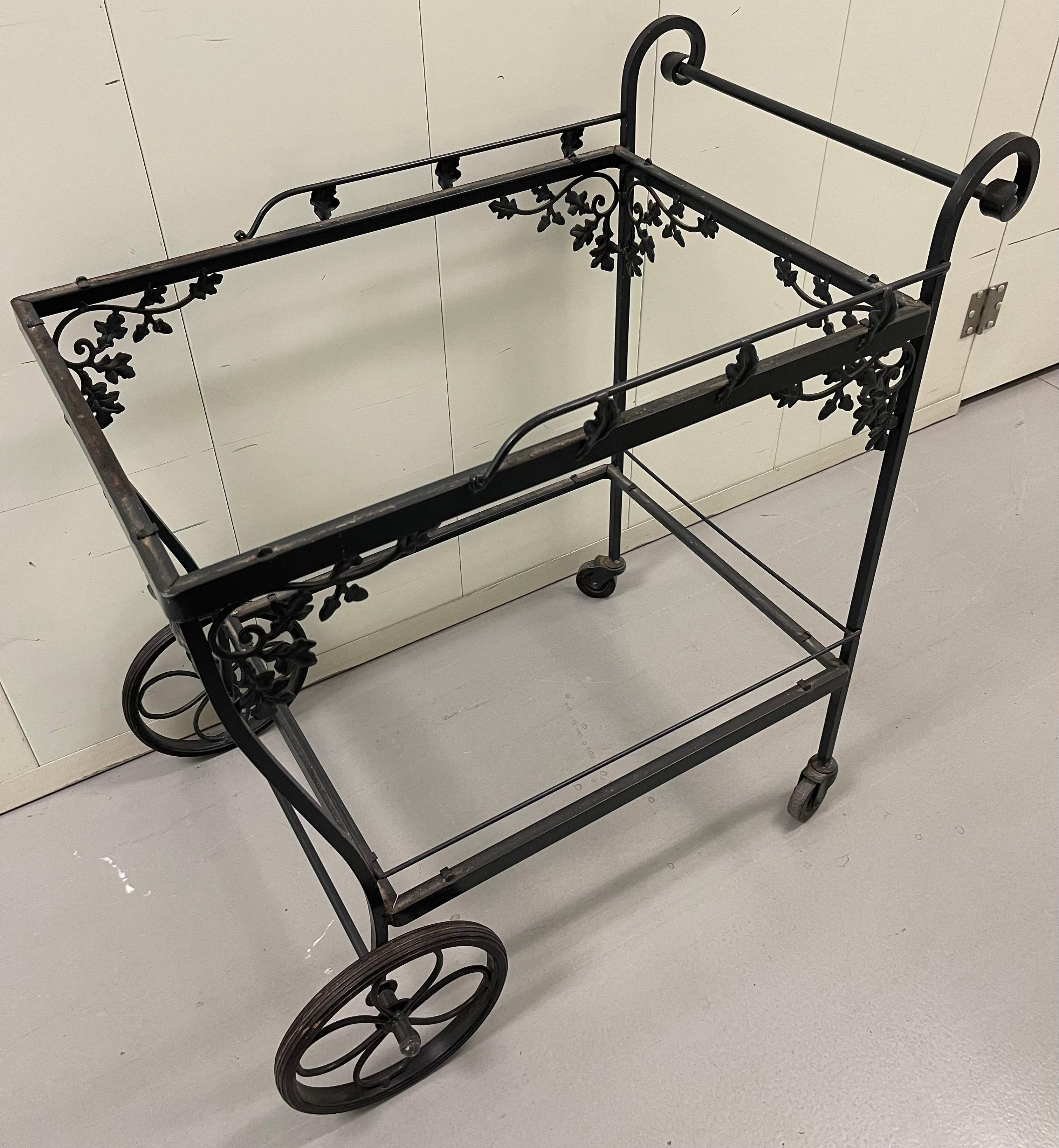 1940s Woodard Orleans pattern outdoor tea cart or bar cart. As found black painted finish. Original wheels are in working order. Glass is NOT included.