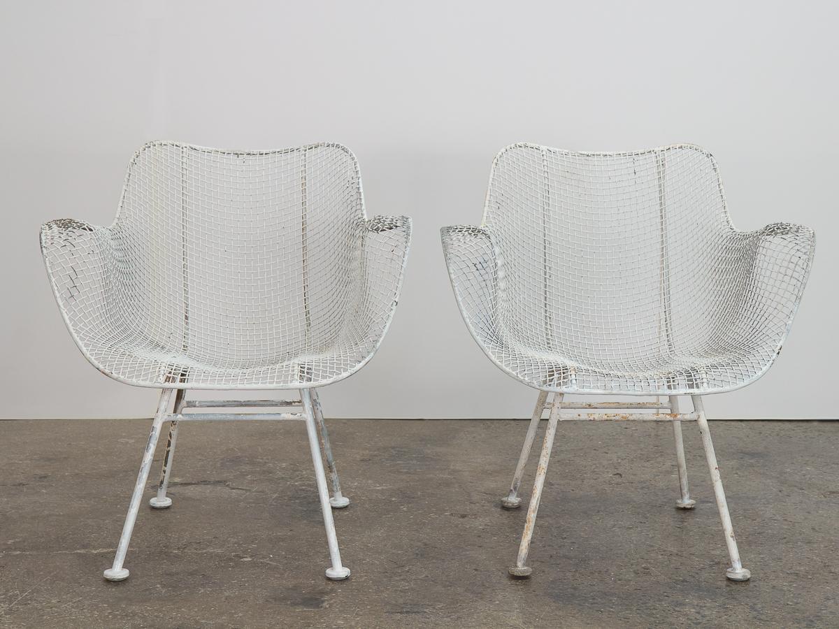 Pair of original Woodard Sculptura armchairs. A versatile option for outdoor entertaining, this set is dining chair height so can be used with a patio table. The wrought iron frames and woven mesh steel seats are strong and can stand all weather.