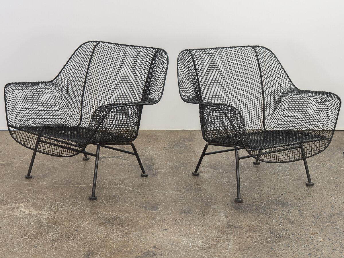 Pair of sculptura garden lounge chairs, designed by Russell Woodard. An airy design achieved by mesh steel on a wrought iron frame. Black satin finish has been recently professionally refinished. Low-slung profile makes these terrific for patio or