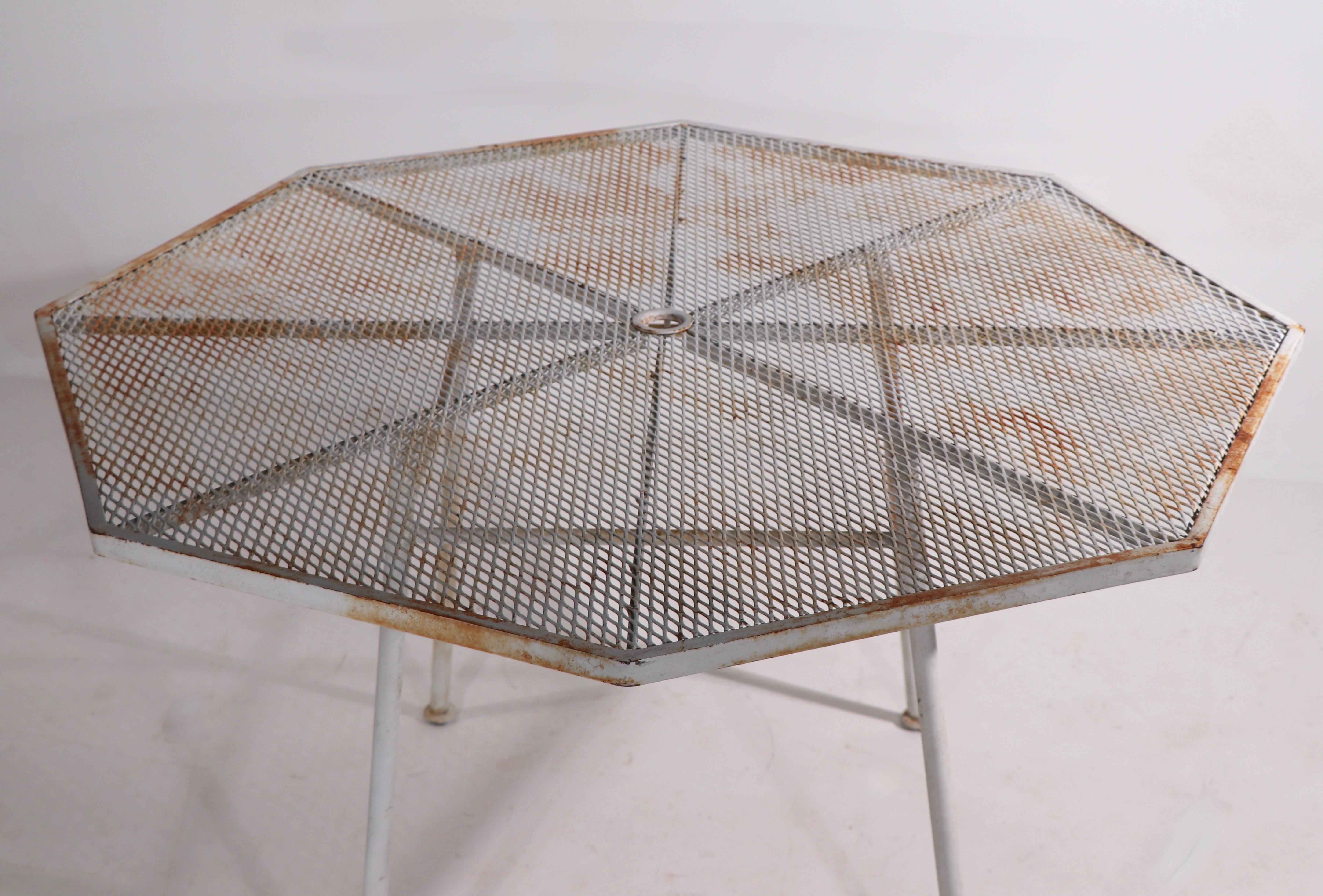 Rare Sculptura garden, patio dining table by Russell Woodard. The table has an octagonal metal mesh top, on four tubular iron legs. The table shows cosmetic wear to the paint finish, but is free of structural damage, weld or repairs. Usable as is or