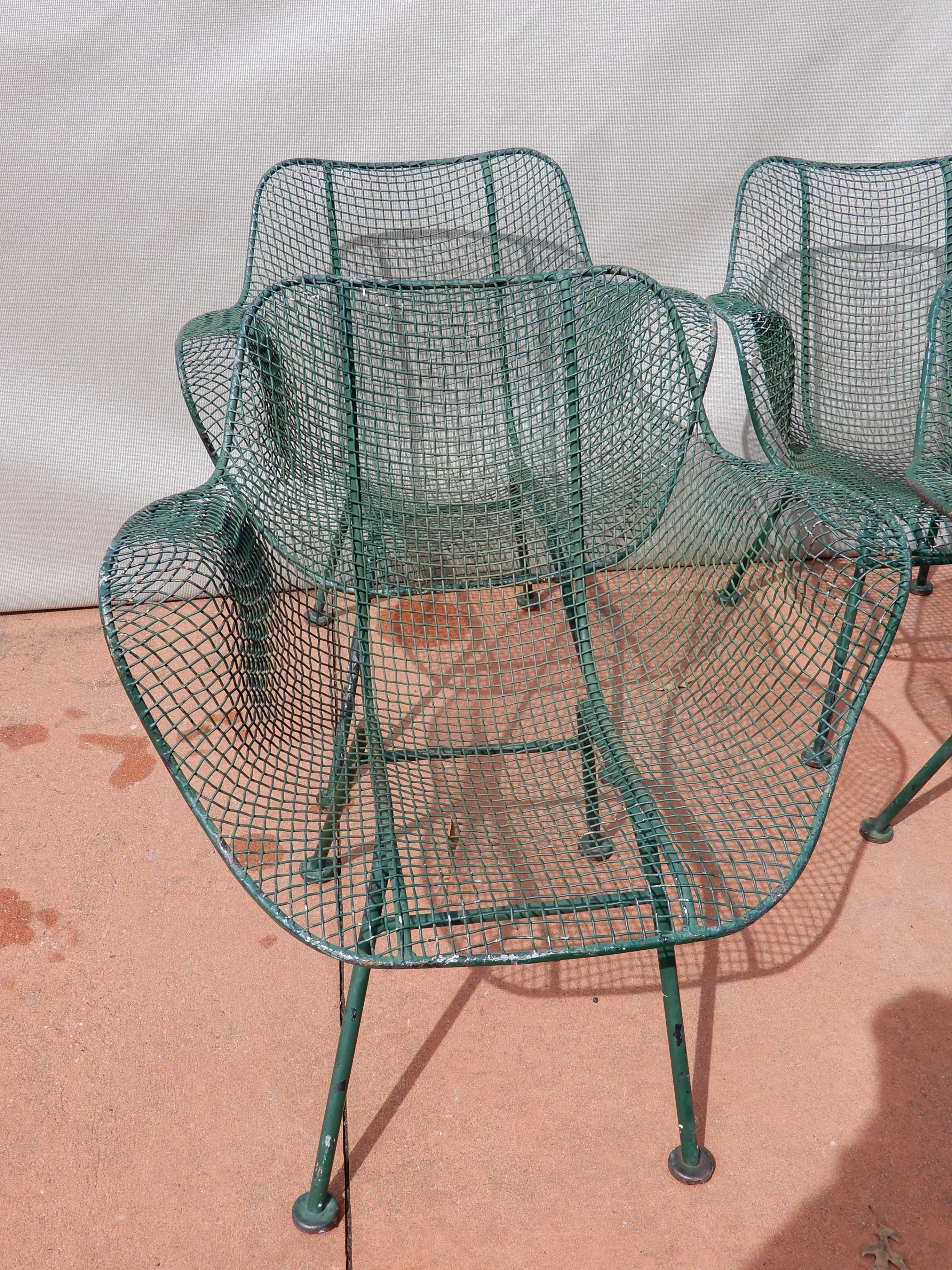 A set of four Russell Woodard sculptura wrought iron and mesh chairs.
These chairs are shown in an ad by Woodard which unfortunately was too small to upload here. The chairs are in a warm light greenish color which is an old painted finish. They are