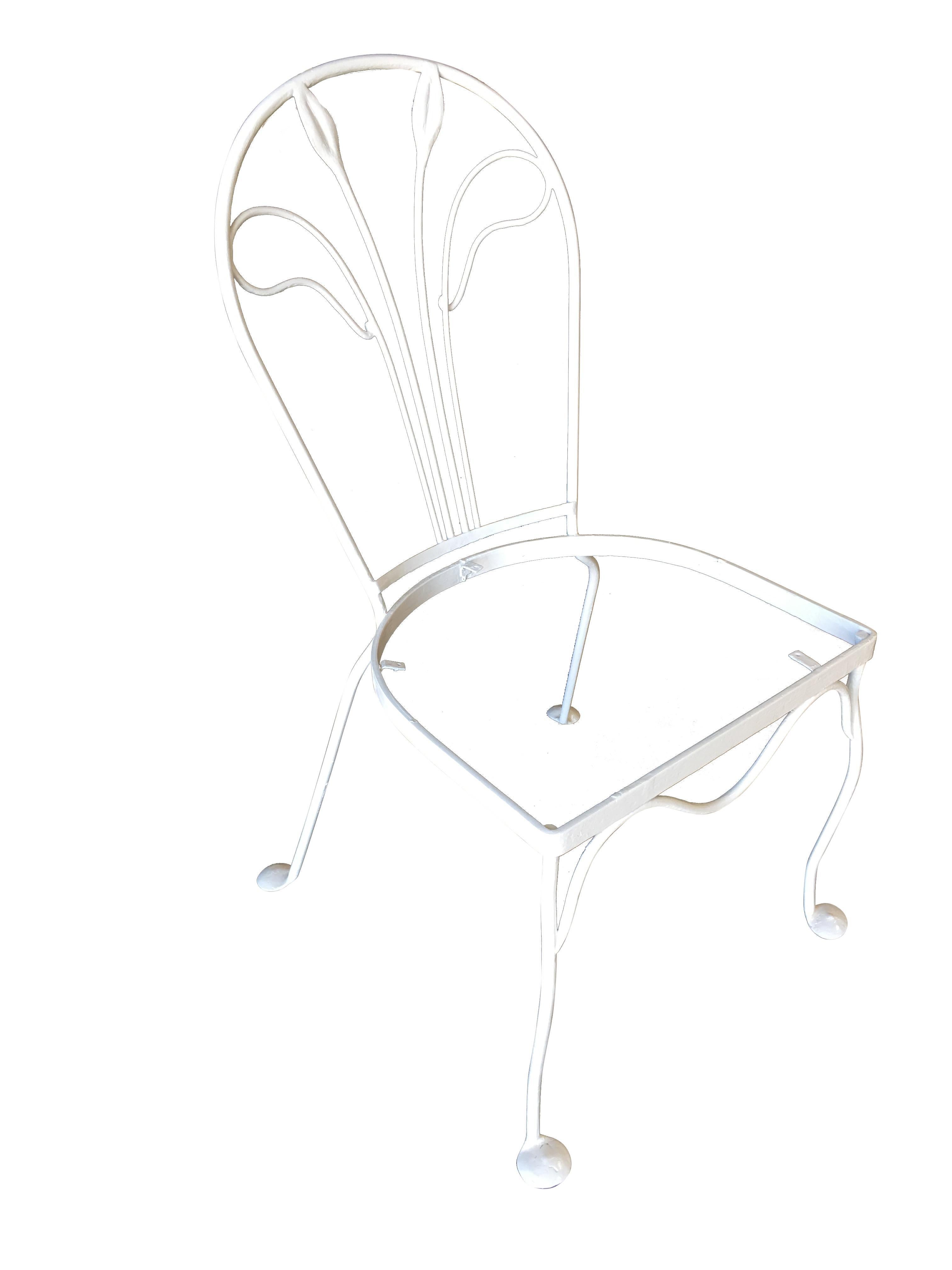 A set of four Woodard rod iron outdoor/patio chair with a distinct tropical leaf backrest. This chair is constructed with solid core iron rods and is finished in your choice of a pure white or black finish with padded seats. All outdoor furniture