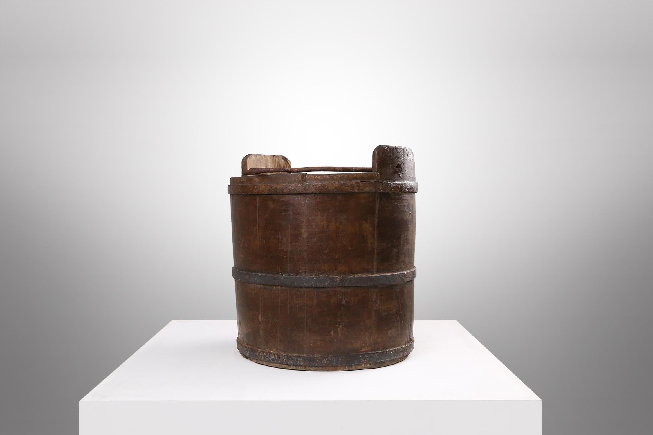 A nice wooden and wrought iron water, grain bucket, fabulous patina on the wood, circa 1860. with handles is on both sides and a raised hand center carrier, triple banded iron slats for the individual wood slats.