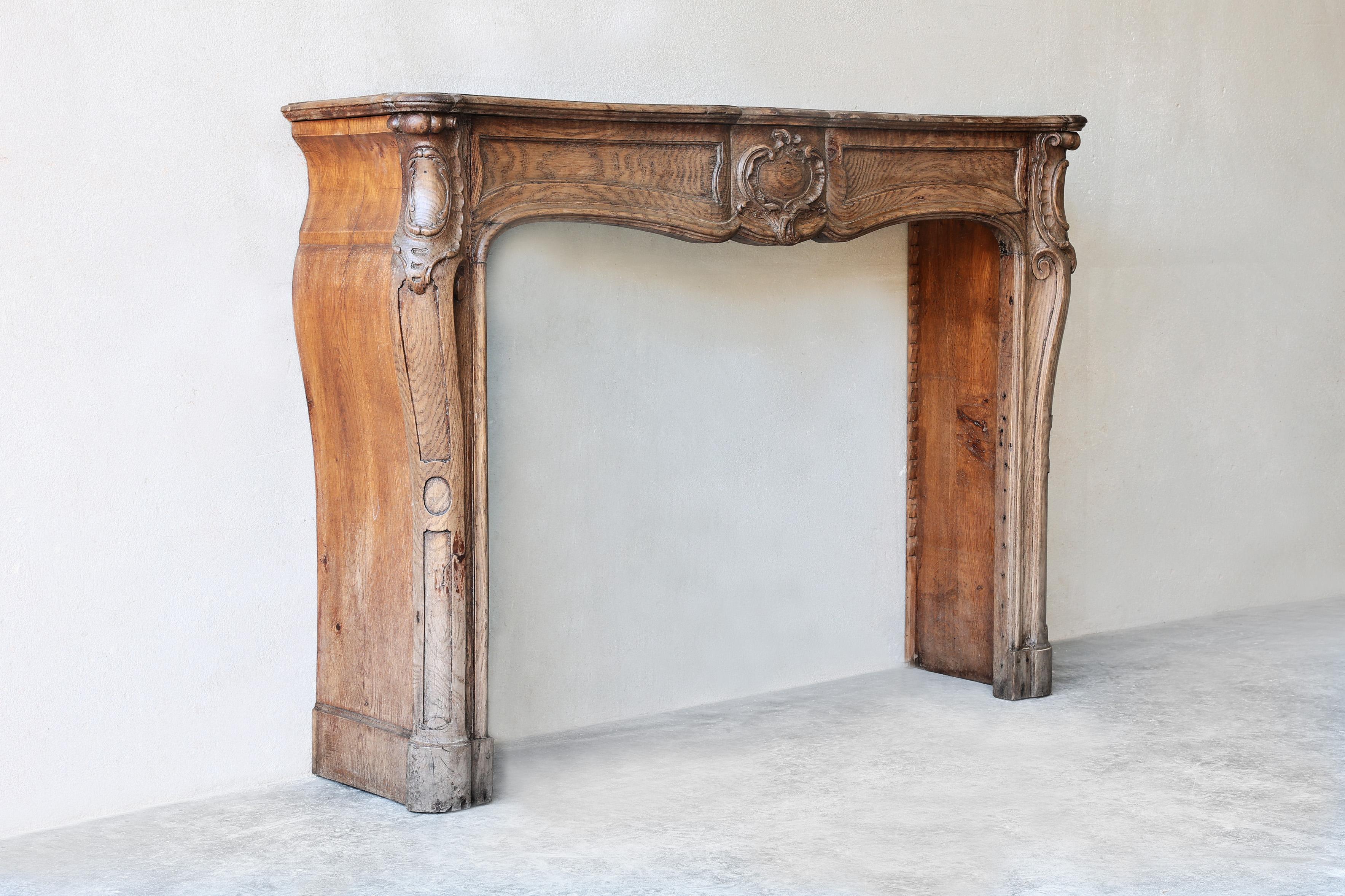 Beautiful oak fireplace in the style of Louis XV. This is an exceptional fireplace that we find every now and then! A beautifully crafted wooden fireplace with beautiful decorations and nice ornament in the middle. A fireplace with a warm appearance