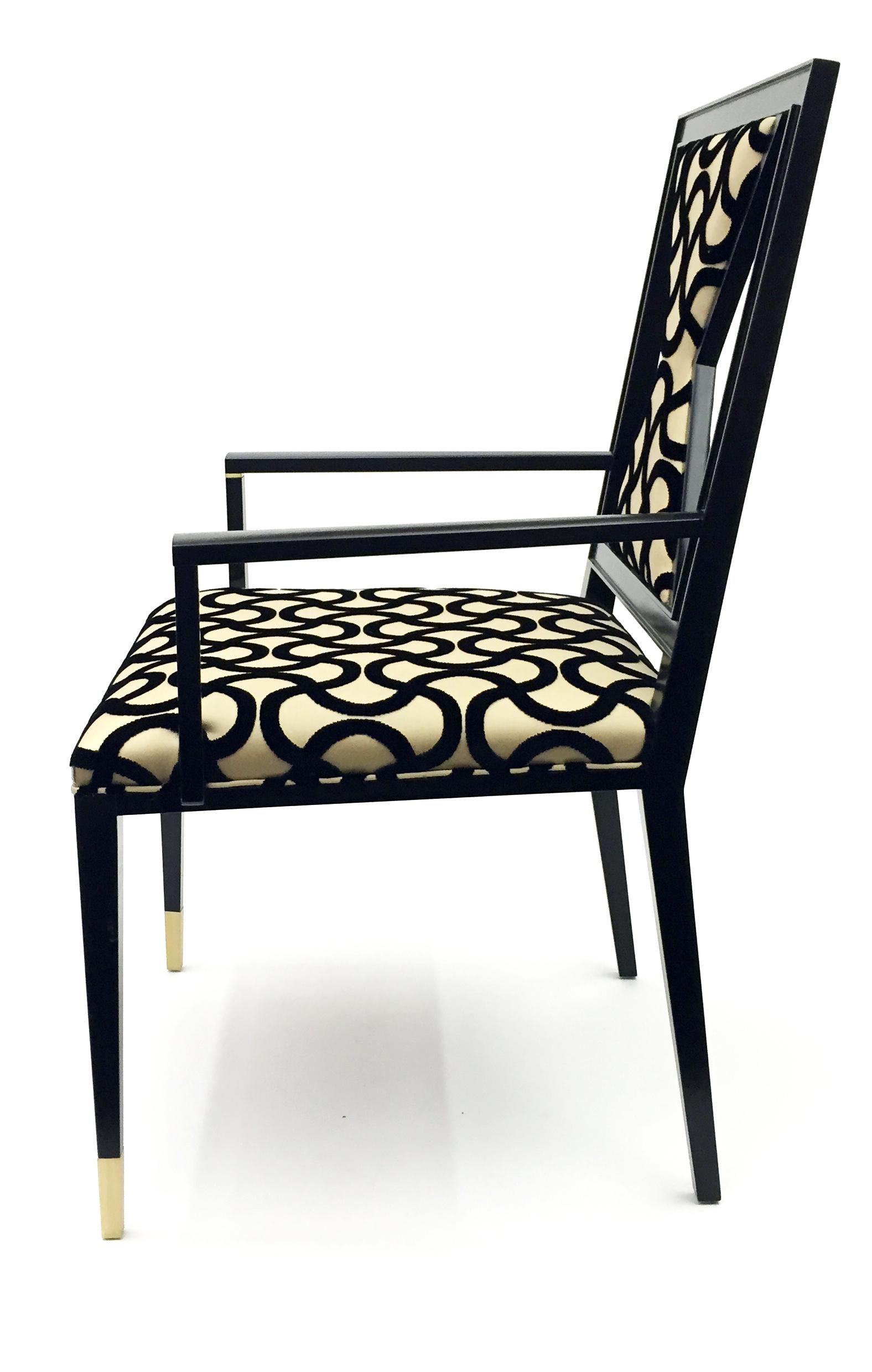 Contemporary wooden armchair design by Juan Montoya. This unique piece has brass details and a geometric shaped backrest. It is upholstered with a patterned fabric which was chosen by the designer to allow movement and bring character to the piece.