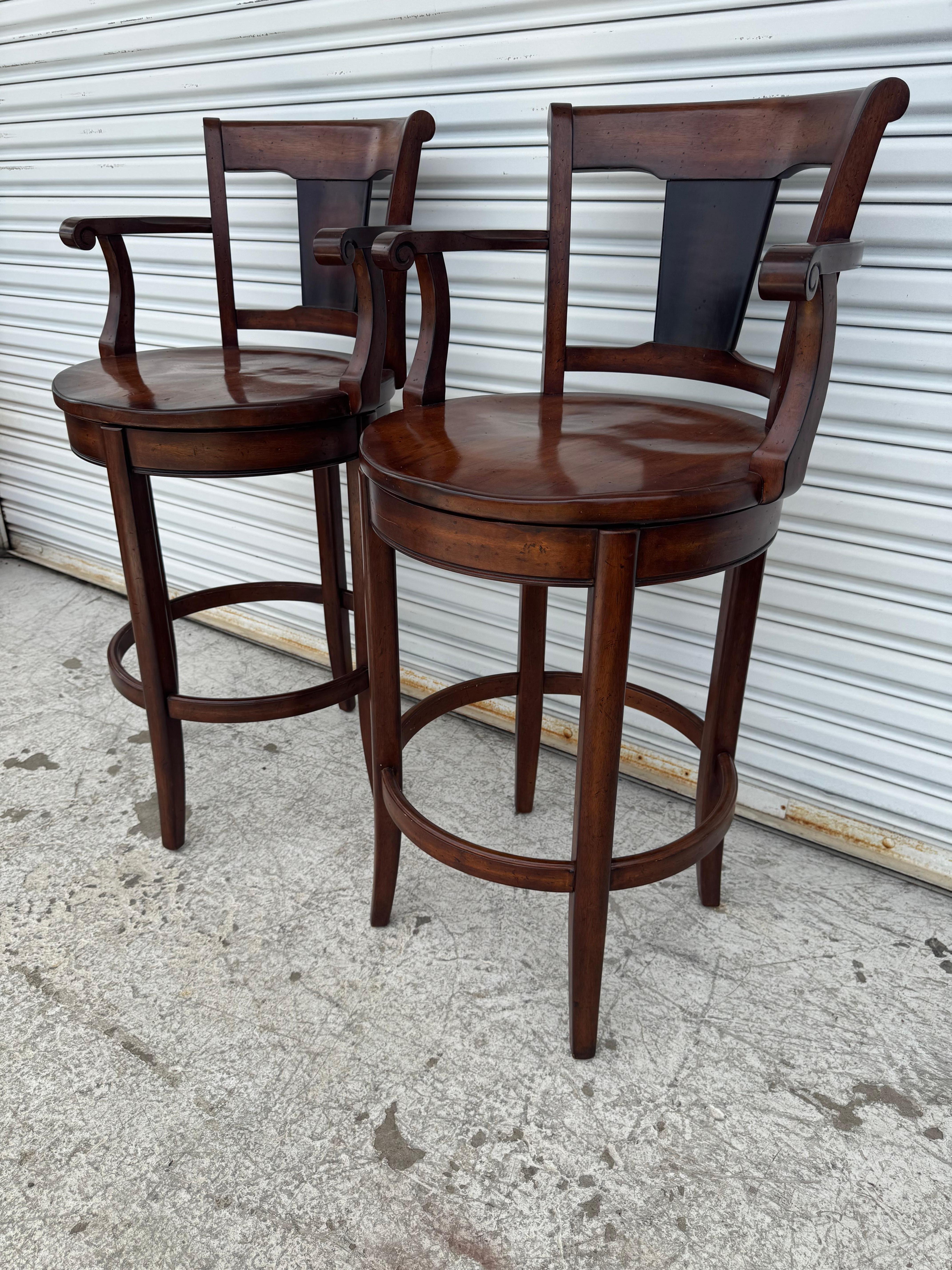 Cette élégante paire de tabourets de bar en bois présente une riche finition en noyer foncé, une assise ronde profilée et un dossier haut de soutien avec un design bicolore unique. Fabriqué en bois massif, chaque tabouret comprend des accoudoirs