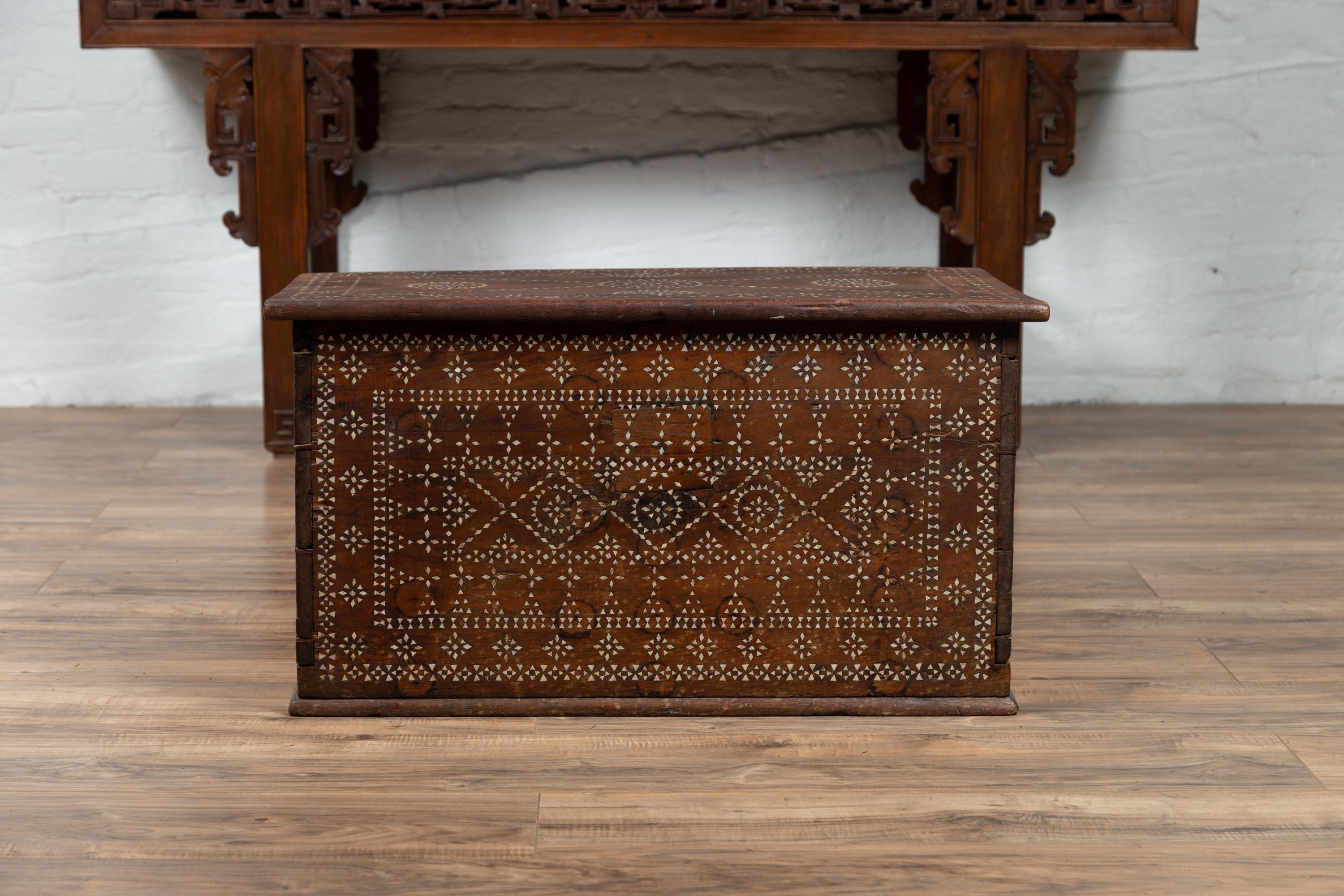An Indonesian wooden blanket chest from Madura, adorned with mother-of-pearl inlay. Born on the island of Madura off of the northeastern coast of Java, this charming blanket chest features a rectangular lid sitting above a rectangular body. Adorned