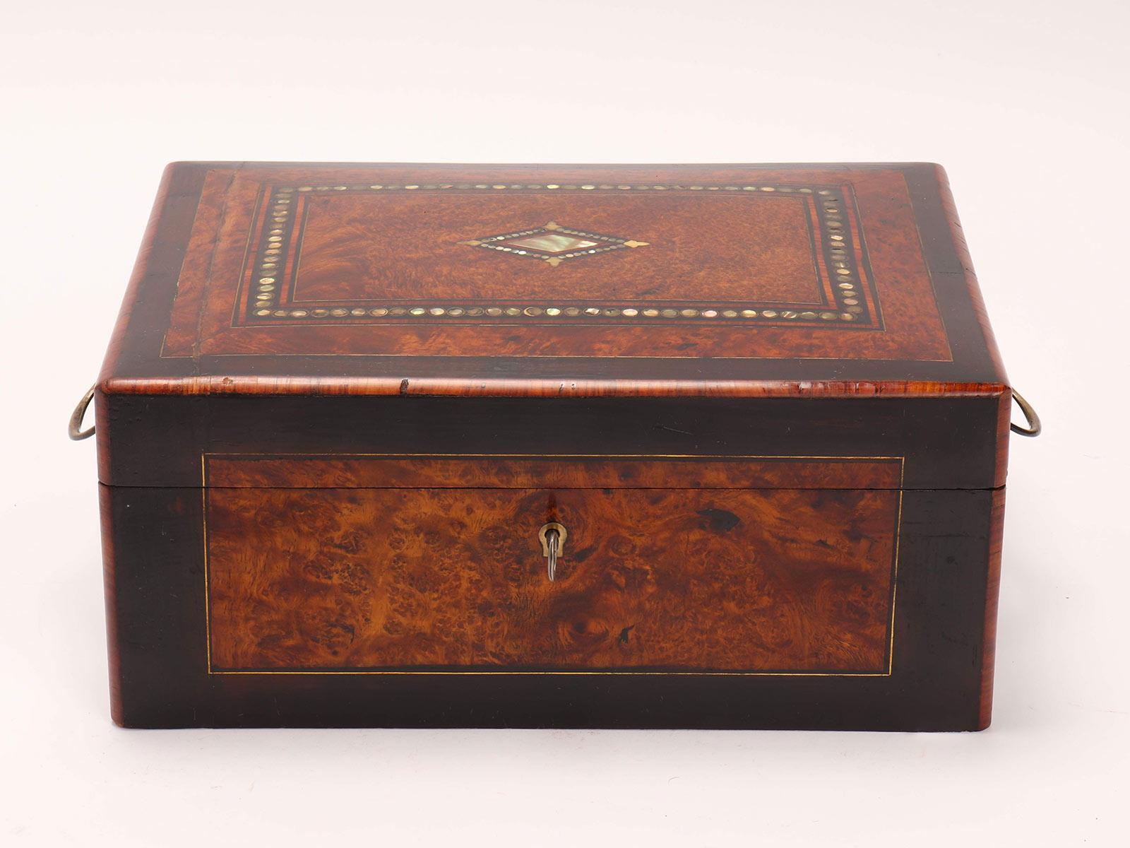 Caja de madera con cerradura y espejo en el interior. El revestimiento exterior es de chapa de madera de brezo, latón con inserciones de nácar, las asas son de latón. Italia mitad del siglo XIX.