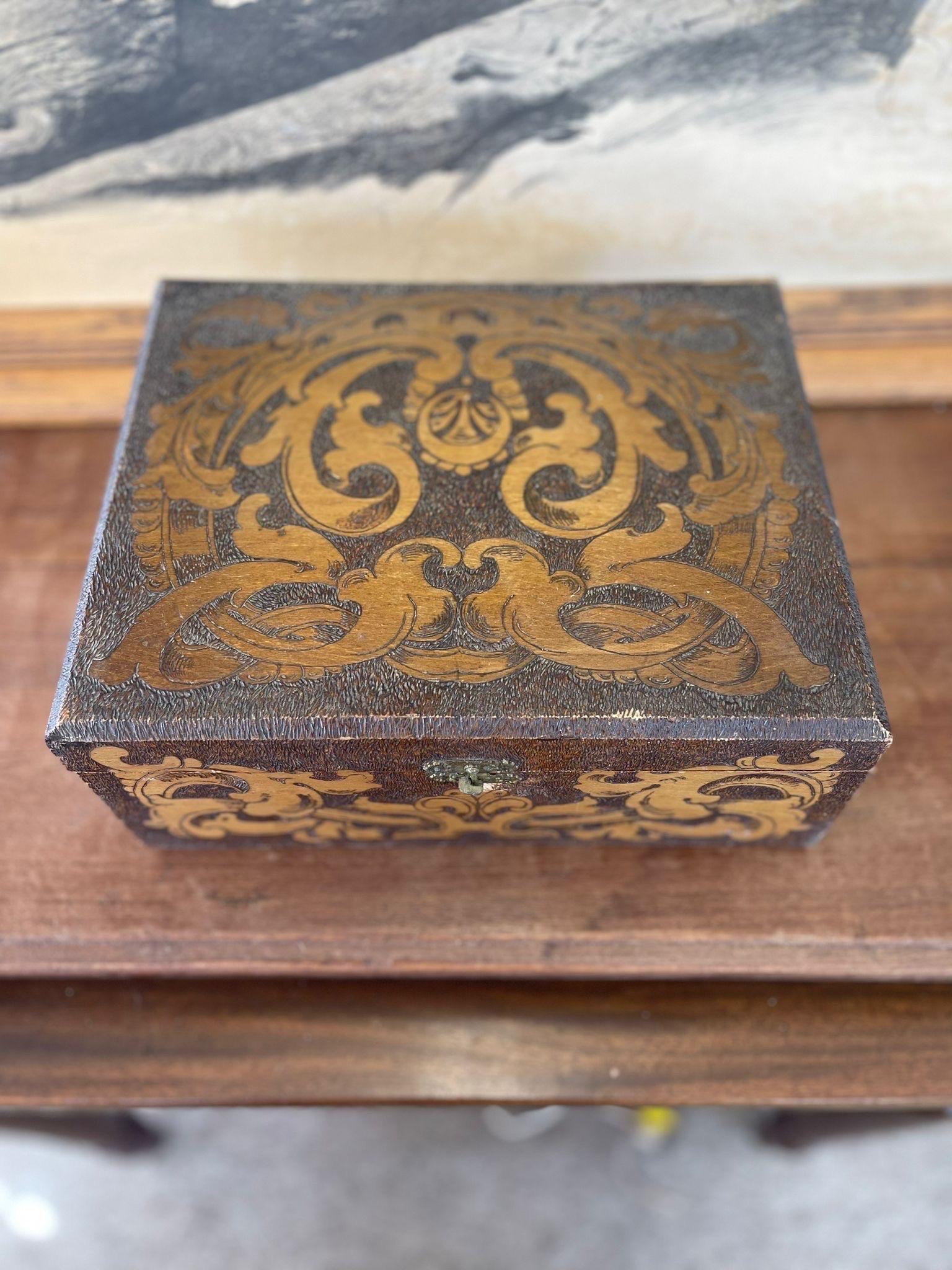 Red Stained Wooden Box with Burned Motifs on All Sides and Top.Cracks and wear Consistent with Age as Pictured.

Dimensions. 11 W ; 9 D ; 5 1/2 He 