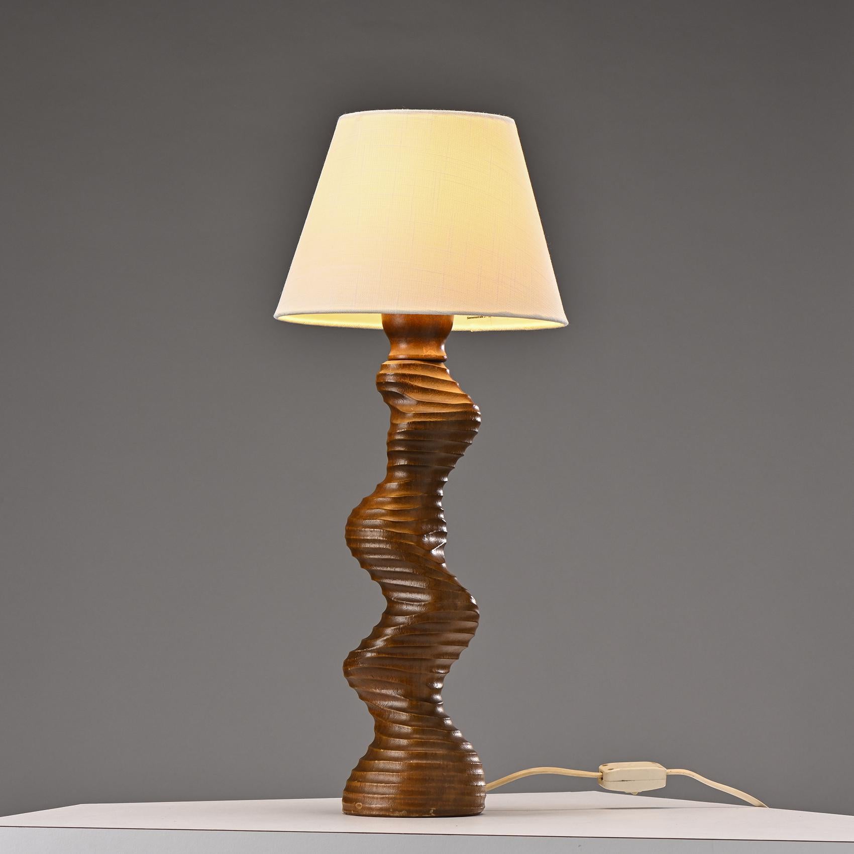 Sculptural and organic wooden table lamp by TEMDE Lights, Switzerland, 1970s.

Featuring a unique, tiered wooden base with a swirling design, this lamp embodies the organic elegance typical of 1970s design. The piece is crafted with exceptional