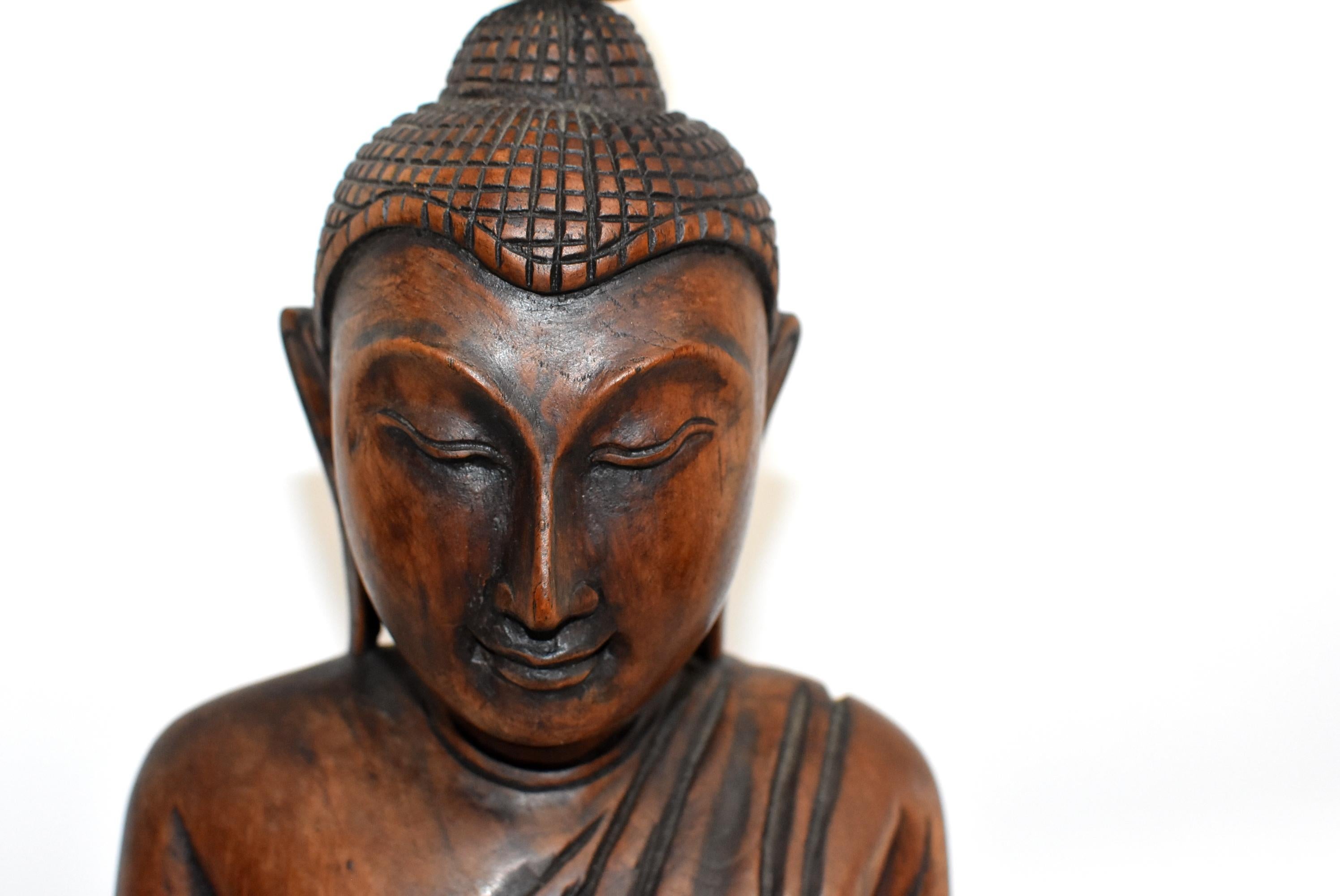A beautiful large statue of Burmese Buddha, hand carved in wood. The work is of a master wood carving artist who is able to convey peace and harmony through this work of art. Buddha has the traditional long ears, curved eye brows and wonderful full
