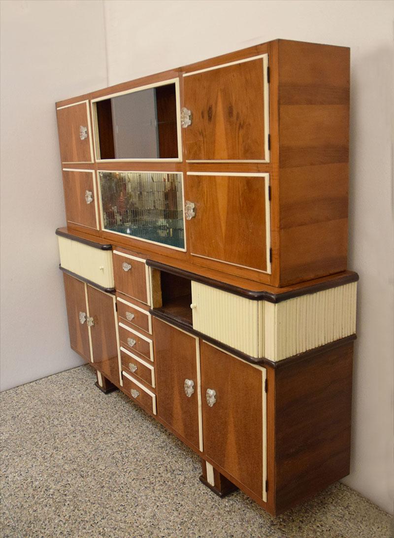 Wooden hall or kitchen cabinet made in the 1950s in Italy.
In wood with two-tone decoration, painted beige pariculars, four open doors, drawer and central flap, sliding side parts.
Upper part with sliding glass cabinet and internal shelf, central