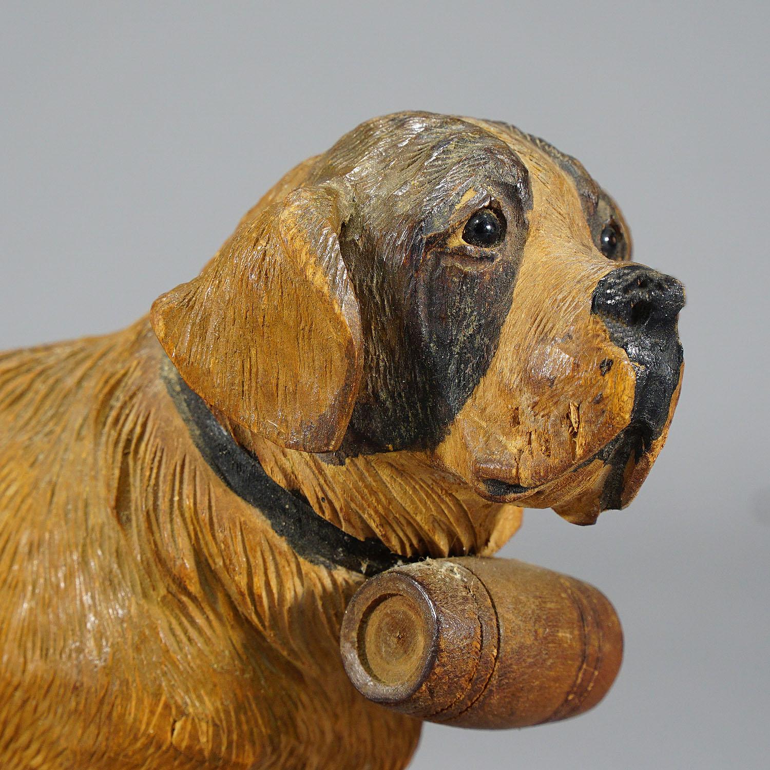 A great early 20th century wooden carved St. Bernard dog sculpture. A very detailed lindenwood carving painted with naturalistic details and with glass eyes. Manufactured in Switzerland in the area of Brienz 1934. Signed 