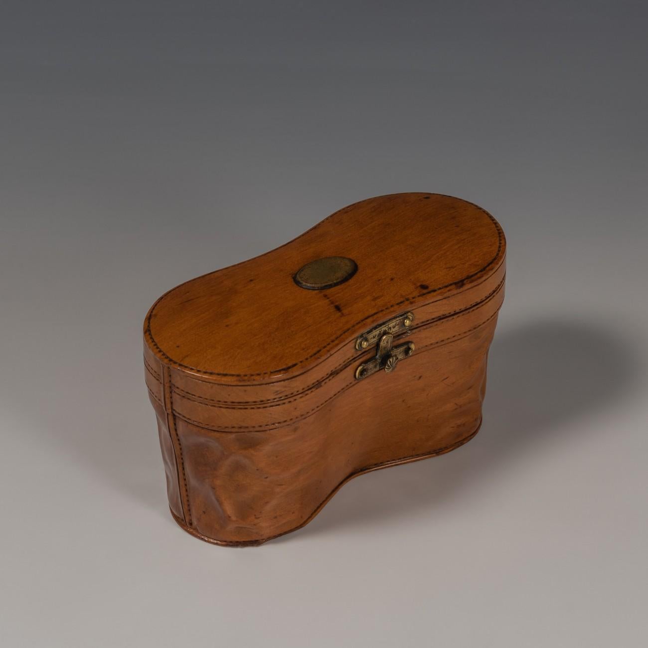 Intricately carved in fruitwood, modelled as a leather case for opera glasses, circa 1900. Lifting the lid reveals two glass inkwells. This exquisitely crafted piece was originally made as a travel item, before the days of fountain