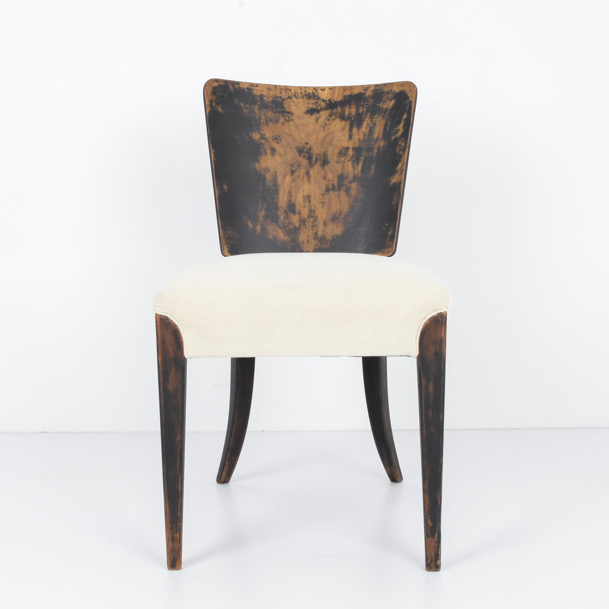 A wooden chair with upholstered seat by esteemed Czech designer Jindrich Halabala, circa 1940. An exemplar of the H-214 design, originally produced by Czech firm UP Brno. The tapered legs of black patinated wood emerge like great fangs to sink in
