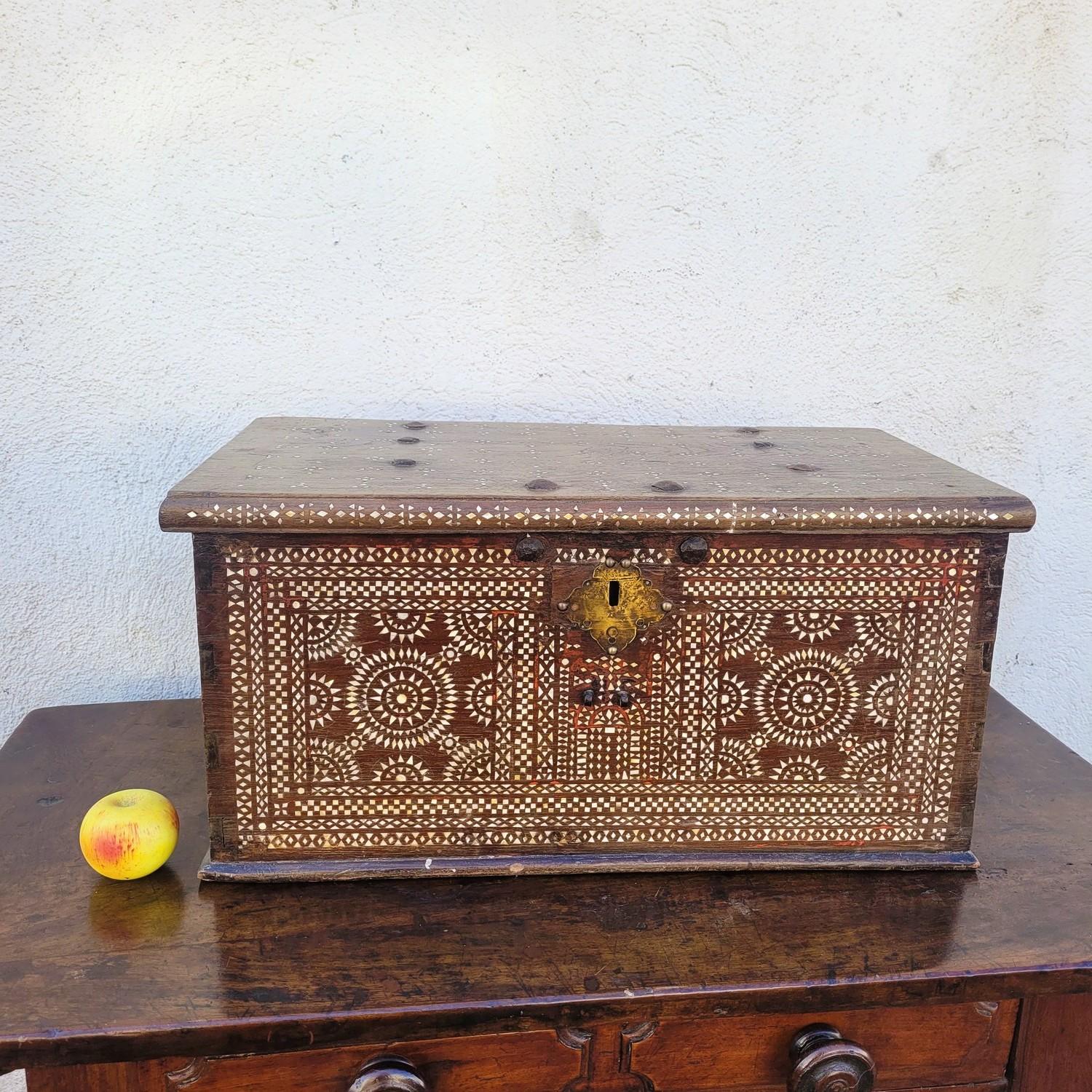 Cofre muy hermoso de madera (¿cedro?) con una fachada ricamente decorada de marquetería de nácar, con motivos geométricos.  

Cada lado del pecho tiene un dibujo diferente.   

Entradas y cerradura cambiadas, desgaste por el uso y piezas que faltan,