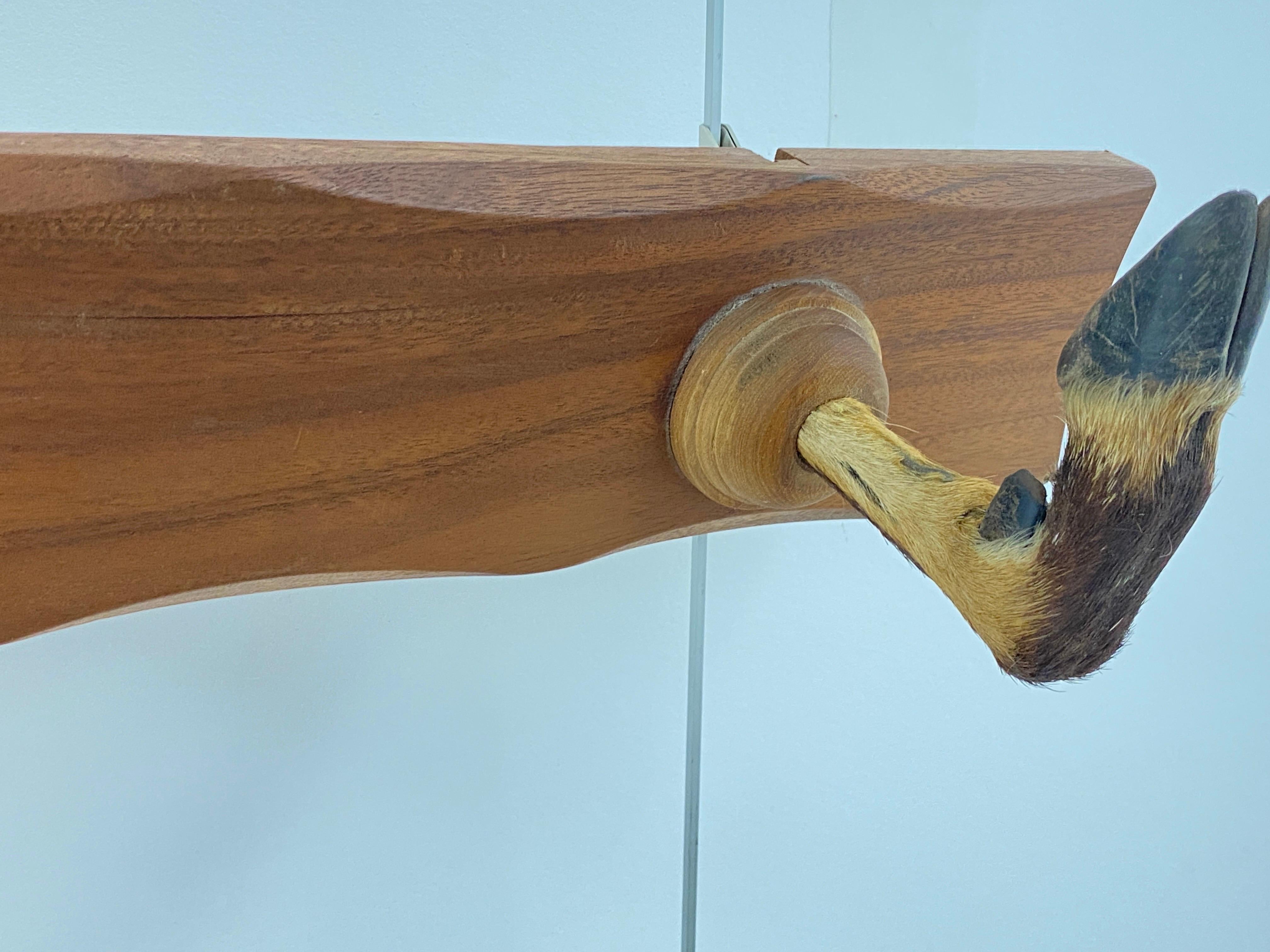 Coat rack in wood, with three hooks in the shape of crowbars. This object was made in France in the 1960s, it is made of brown wood and two crowbar-shaped hooks.