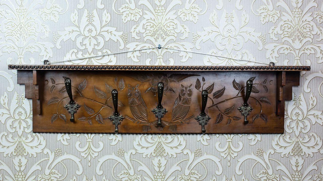 Wooden Coat Rack From the 1940s in Dark Brown

Wooden, pre-war clothes rack with five hooks and a narrow shelf. The back panel features a relief decoration with a motif of tree branches and birds. The rack is in particularly good condition and has
