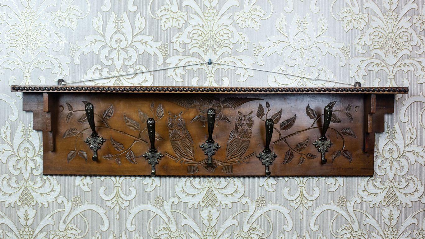 Holzgarderobe aus den 1940er Jahren in Dunkelbraun

Hölzerner Kleiderständer aus der Vorkriegszeit mit fünf Haken und einer schmalen Ablage. Die Rückseite zeigt ein Reliefdekor mit einem Motiv aus Ästen und Vögeln. Das Gestell ist in besonders gutem