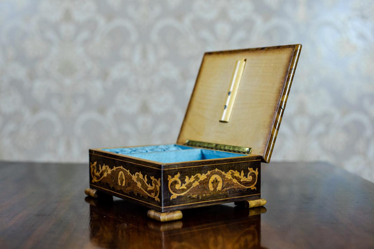 We present you a small coffret with a richly inlaid outside.
The inside is lined with blue satin with padding.
There is a musical box in the coffret.

The mechanism is winded up from below.

This item is in very good condition.
