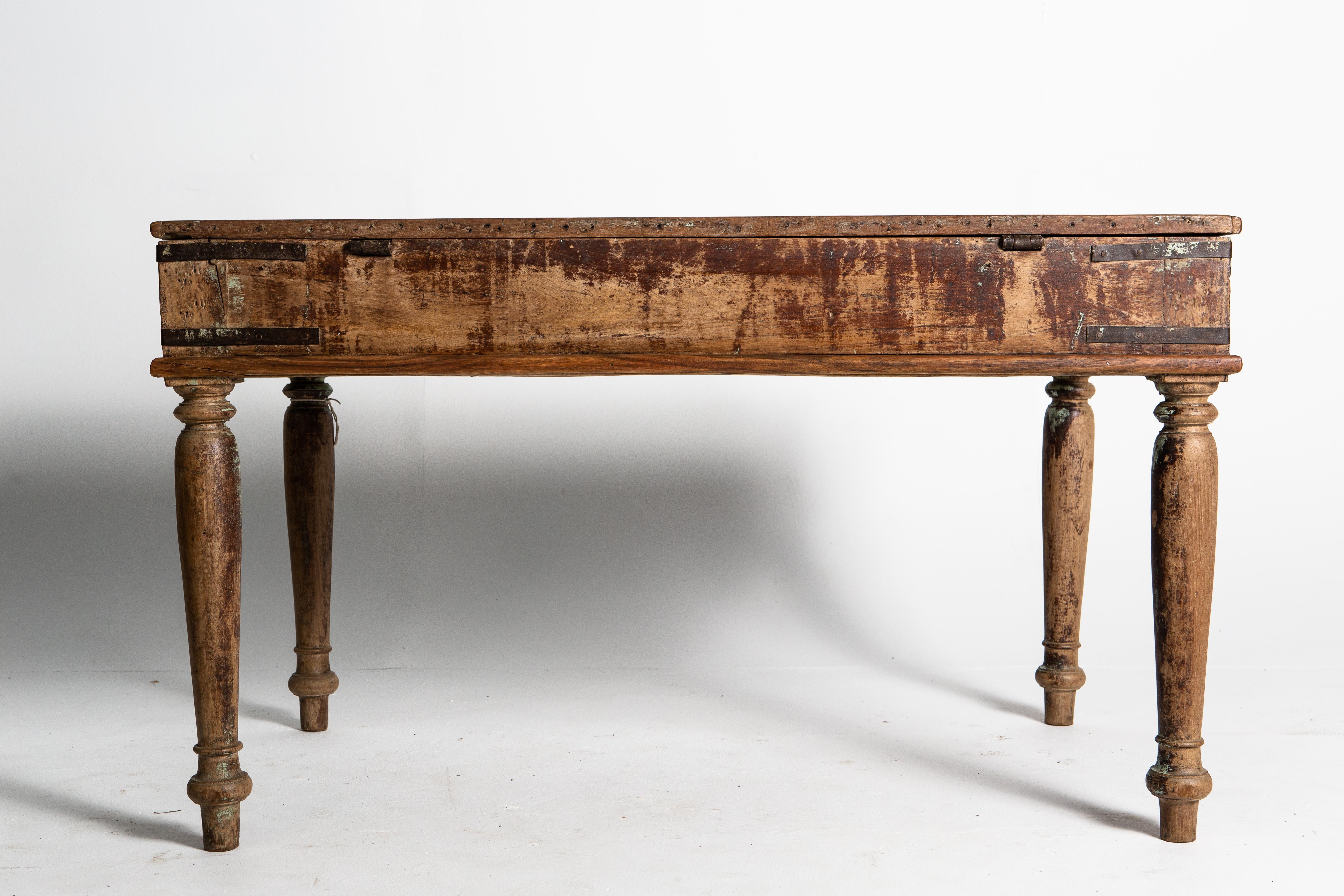 This rustic desk is made of teak and has remnants of its original patina still visible. The piece has wear consistent with age and use.