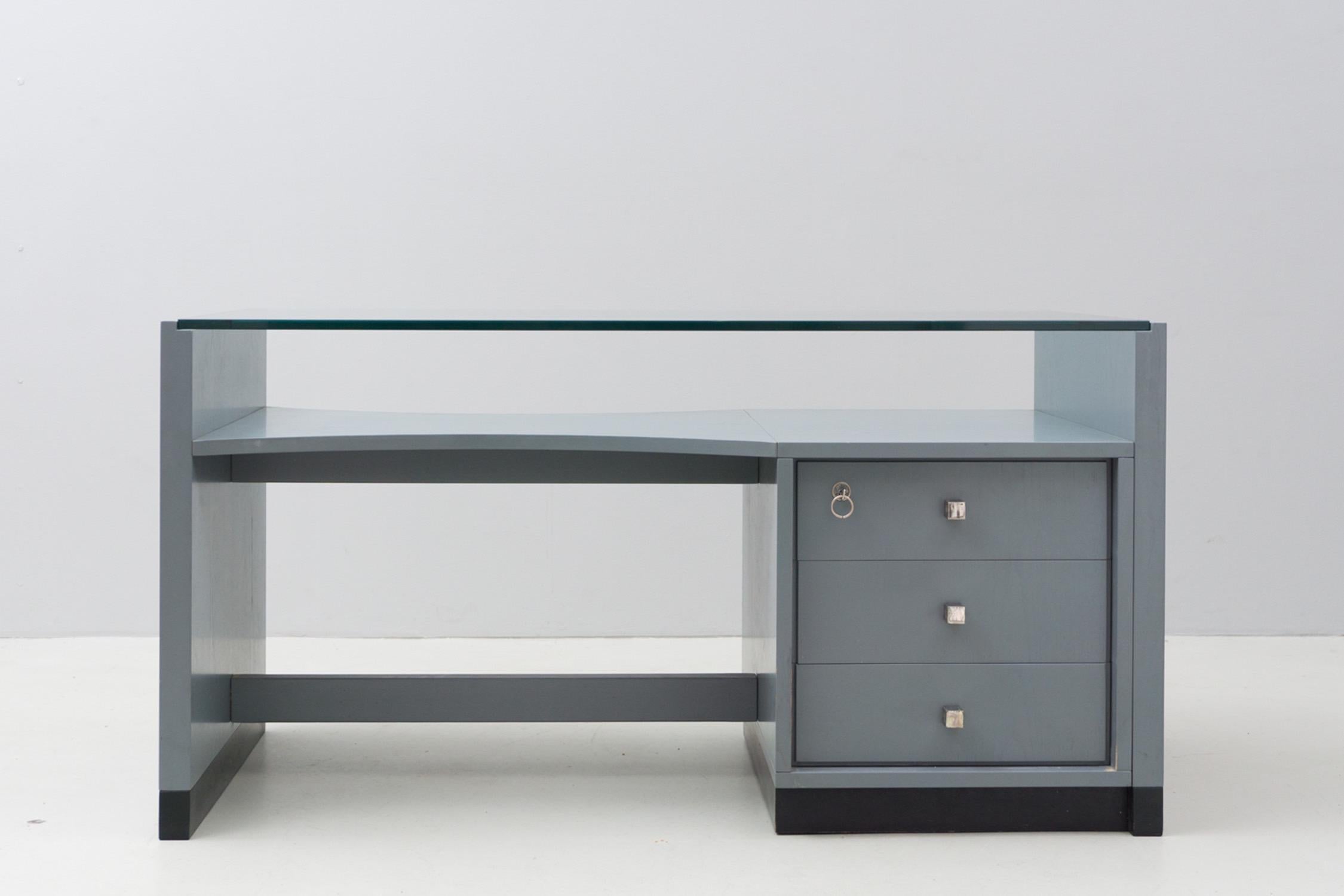 This elegant and minimalistic desk has a wooden construction, with the original lacquer in blue-grey. The top is made of glass plate, handles made of matt-chromed metal.
Listed Parisi Archive Como.