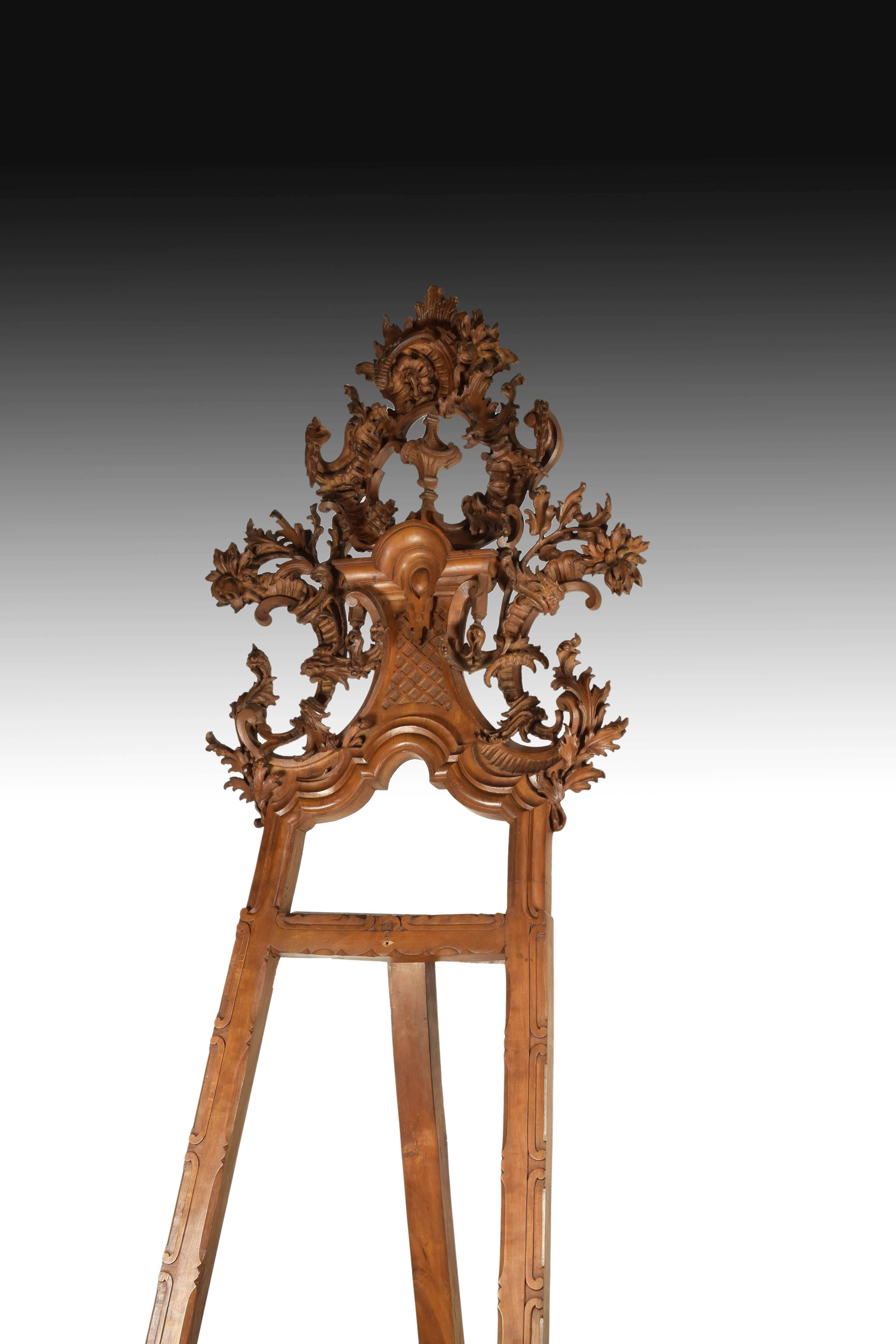 Magnificent carved wooden easel decorated, high, with a tuft of vegetal motifs framed a curved pediment and simple motifs on the sides. The support for the canvas or paper is made thanks to a horizontal crossbar and two moldings with vegetable