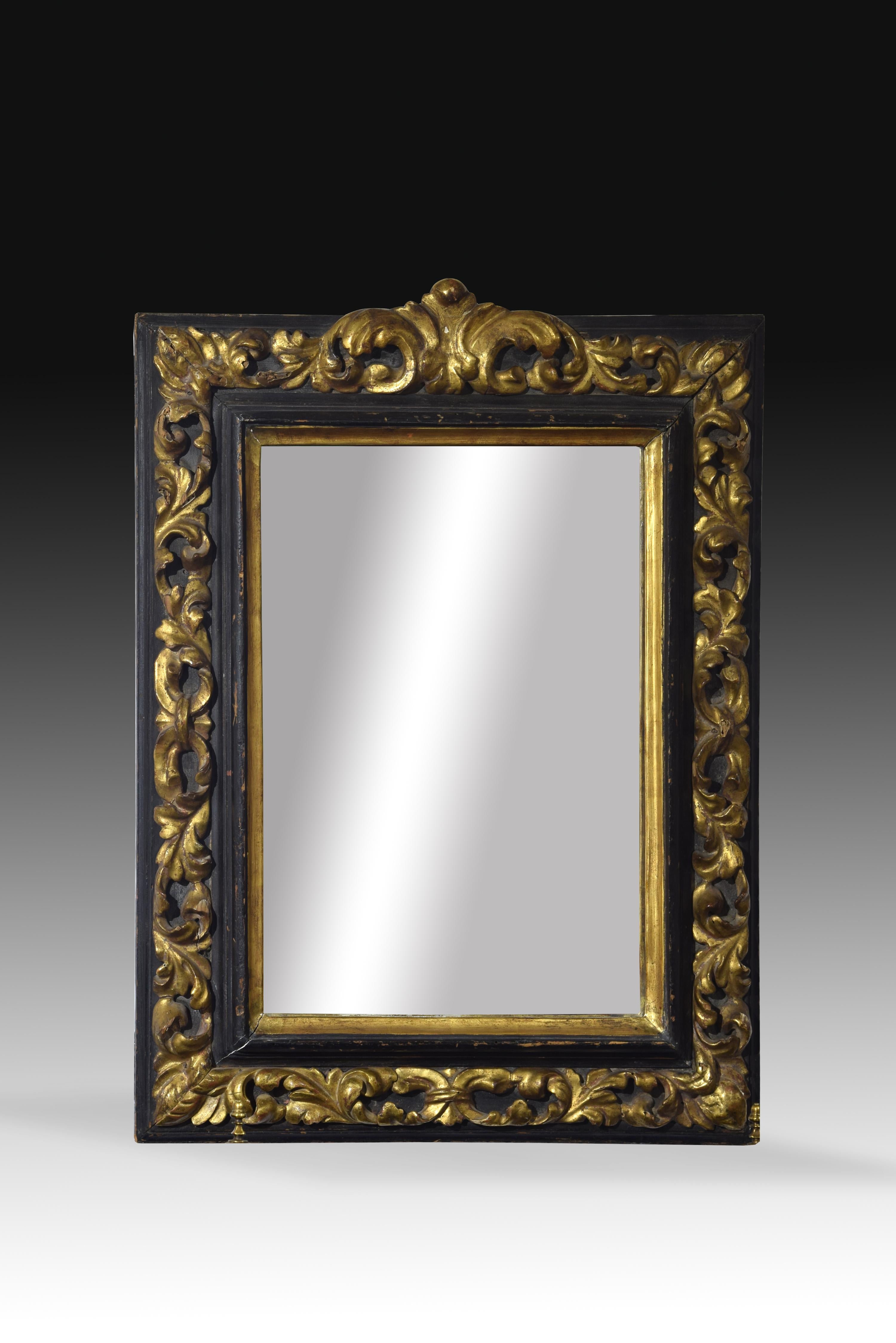 Rectangular frame made of carved and polychrome wood, decorated on the front with plant elements, larger and with more volume in the upper central part, as was usual in these examples, leaving these golden motifs standing out against the dark