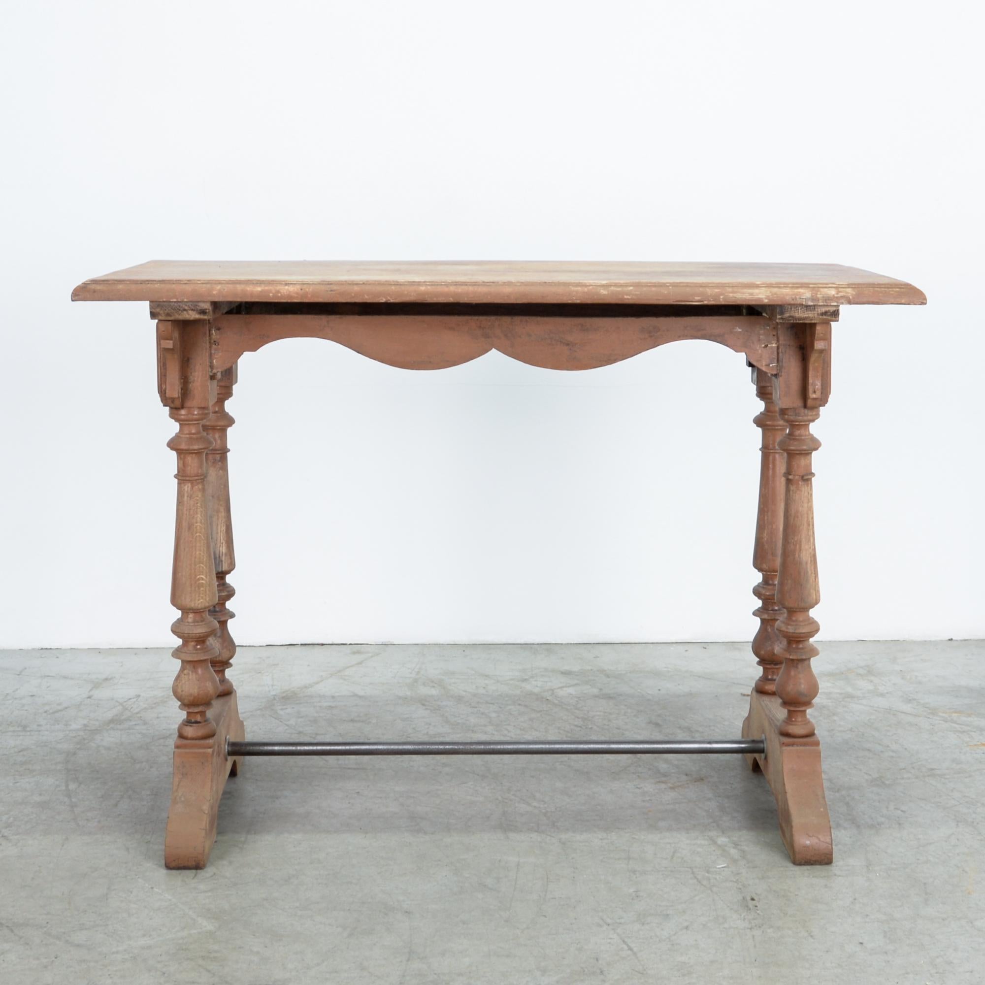 From France, circa 1900. An eclectic French street style, influenced by classical pieces and the necessities of the cafe. A typical design with two sturdy wooden legs, a scalloped wooden brace, and a metal bar suspended below. Handsome patina and
