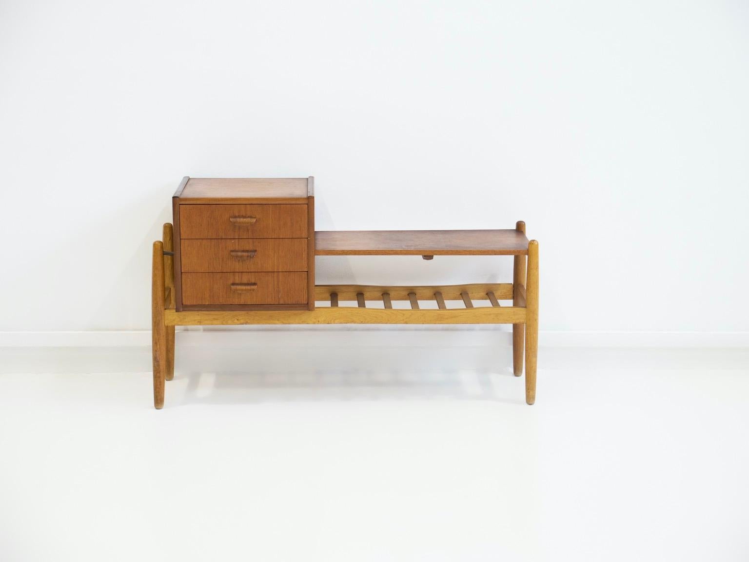 Small side or console table with a rack for shoes, a shelf and three drawers. Made of veneered teak and oak. Round tapered legs and brass details. Designed by Arne Wahl Iversen and manufactured in Denmark. Great piece for the entrance or hallway.