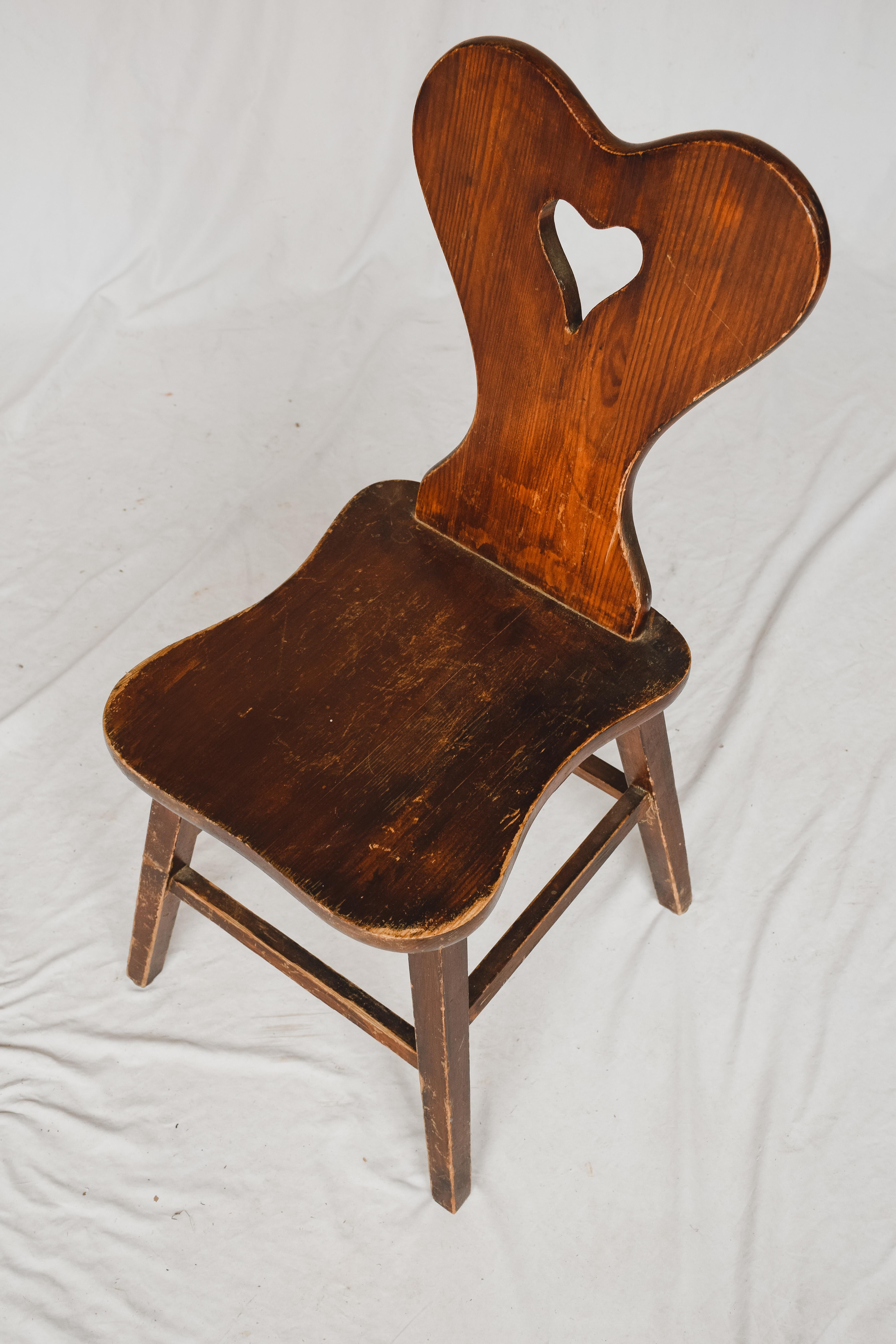 Rustic and simple these wooden chairs with an open heart carved in the back are the perfect companion to any desk or entry table. Purchased in Europe these wooden chairs almost mirror the milking chairs found in all over the Netherlands. This chair