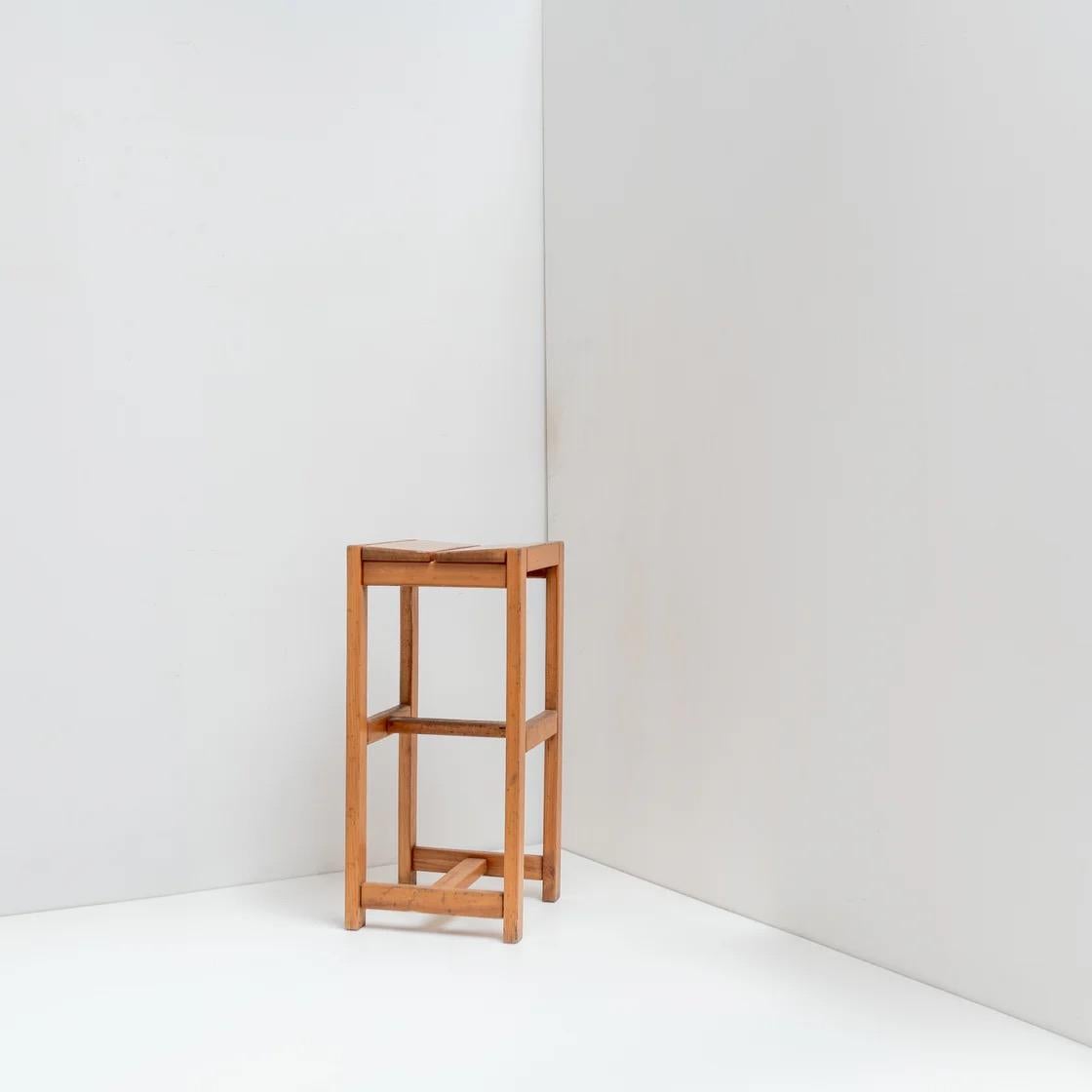 Un taburete de madera con una silueta clara y arquitectónica. Su sencilla construcción y su cálido tono natural le confieren una presencia tranquila, funcional pero escultural, adecuada como asiento o como simple acento en el interior.