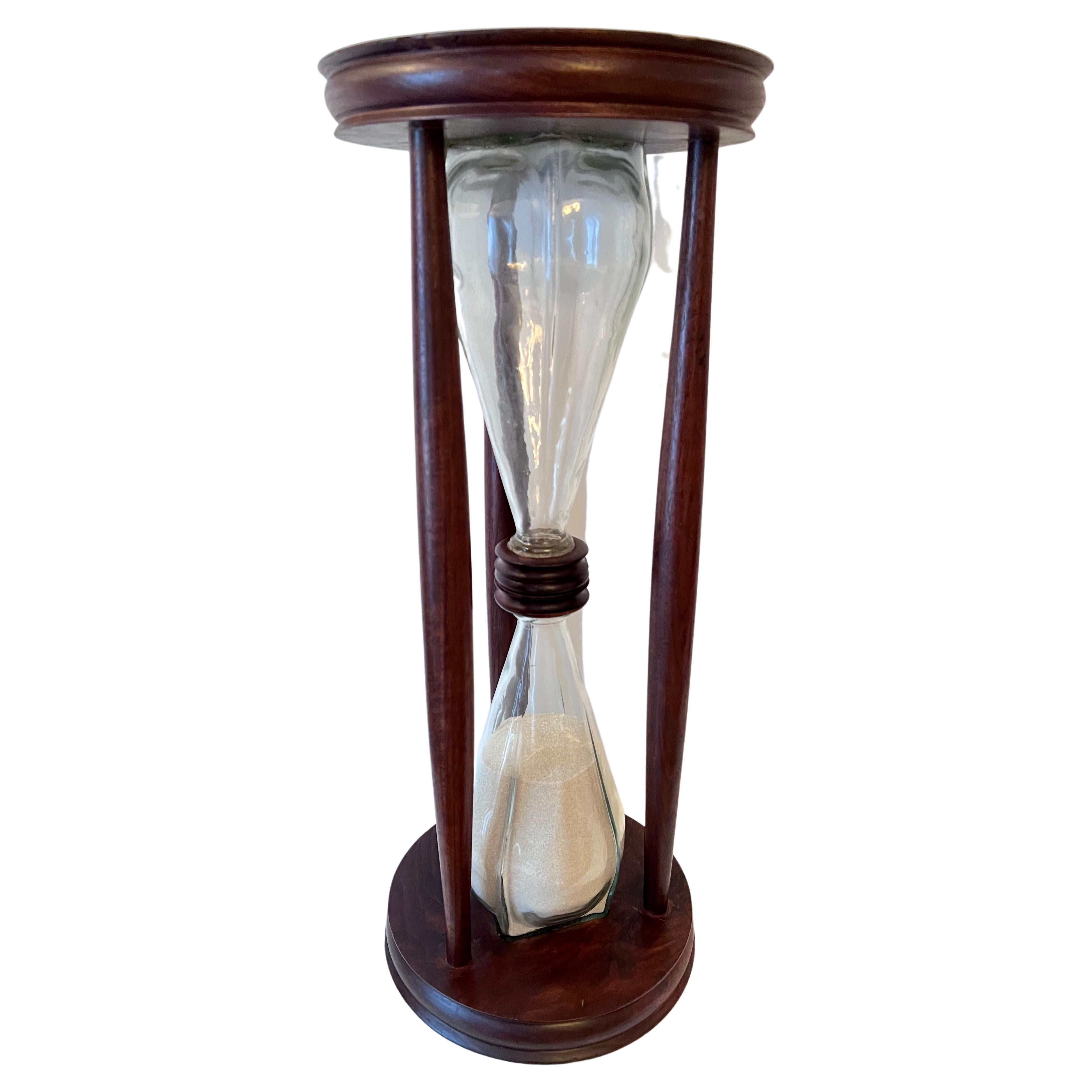 Hour Glass or Sand Timer of solid wood frame, in Mahogany or Walnut. The piece is a compliment to any space and because of its clean lines and angular glass would be spectacular in a modern home. 

The sand flows nicely and we are not sure of the