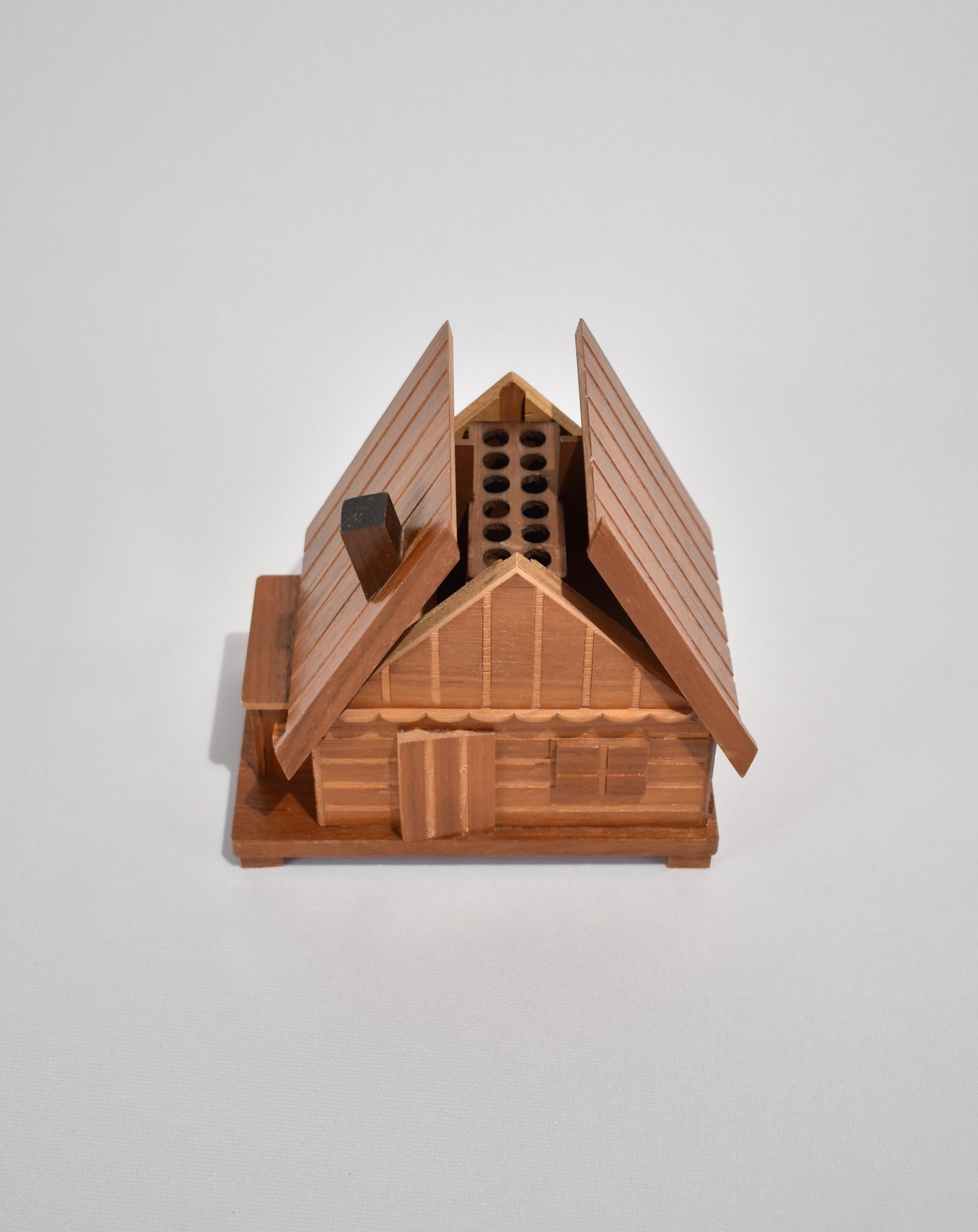 Vintage, wooden music box cigarette holder in a whimsical house design. Box is hand wound and includes a release button on the side of the house. When pressed, an instrumental version of Smoke Gets in Your Eyes plays as it opens to reveal twelve