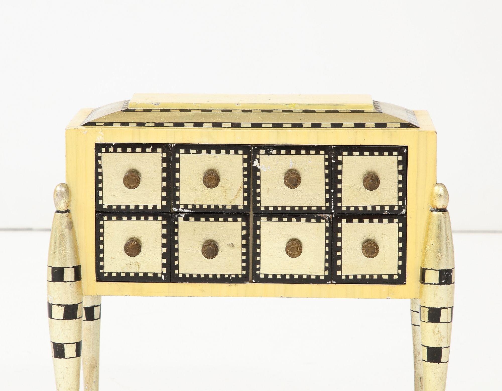 Une délicate boîte à bijoux en bois avec de multiples tiroirs et des poignées en bois doré et laqué.