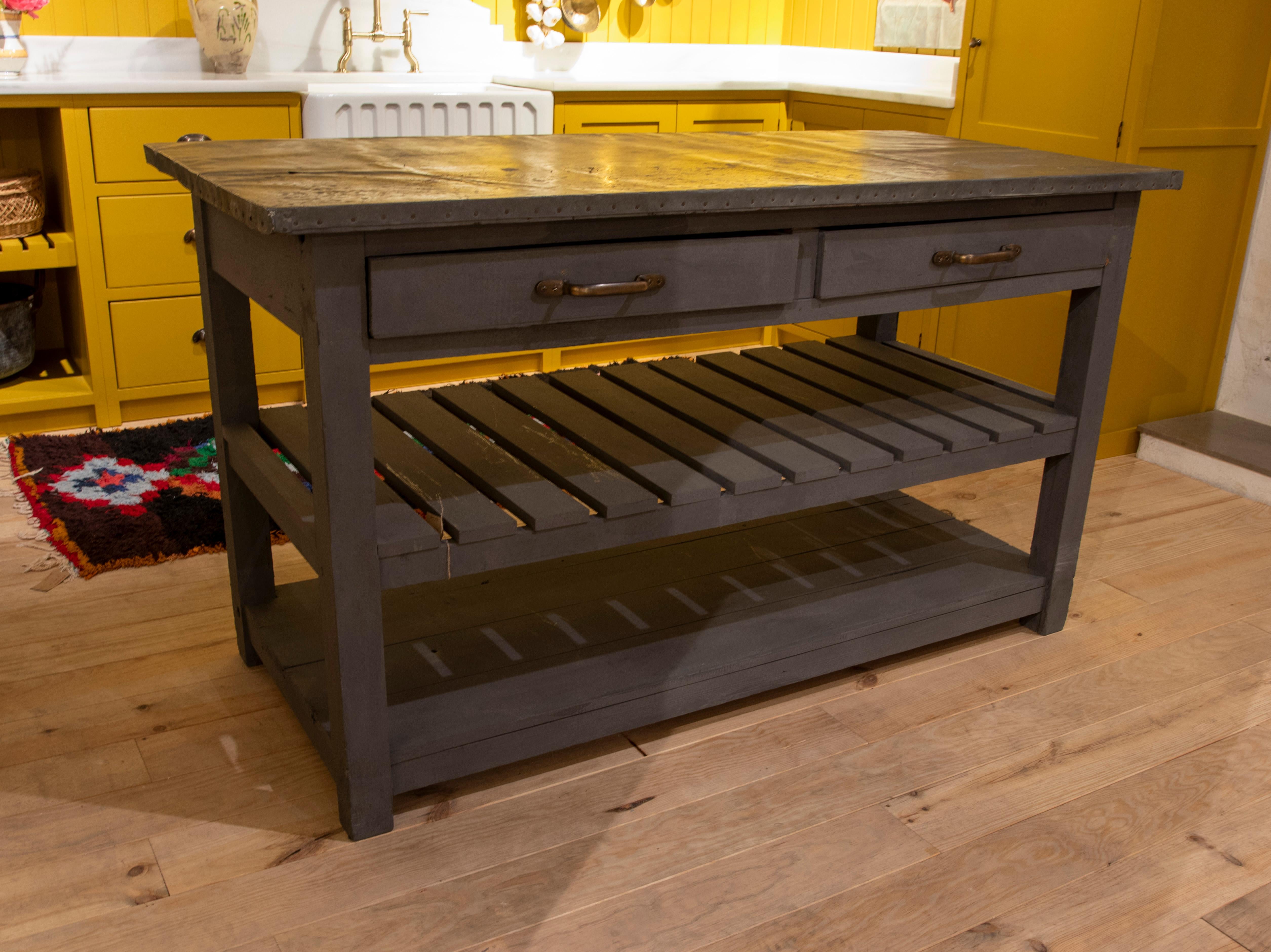 Wooden Kitchen table with metal top, drawers and two lower shelves.