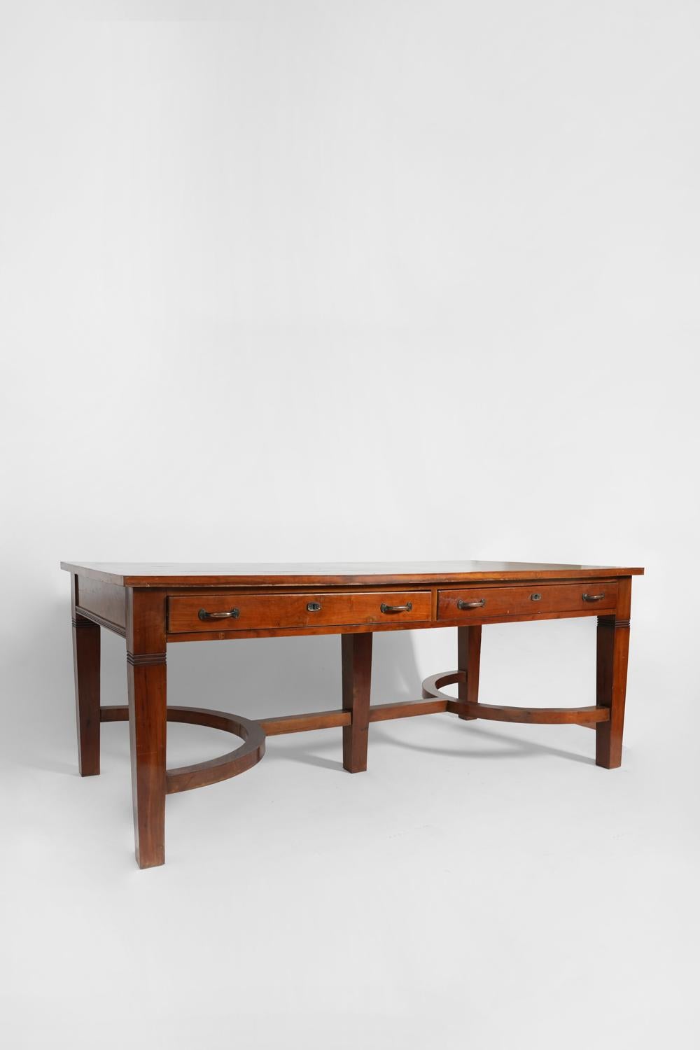 Dark wooden library table supported by five feet connected to each other and opening by four drawers designed by Olaio. Portugal, 1940s. 