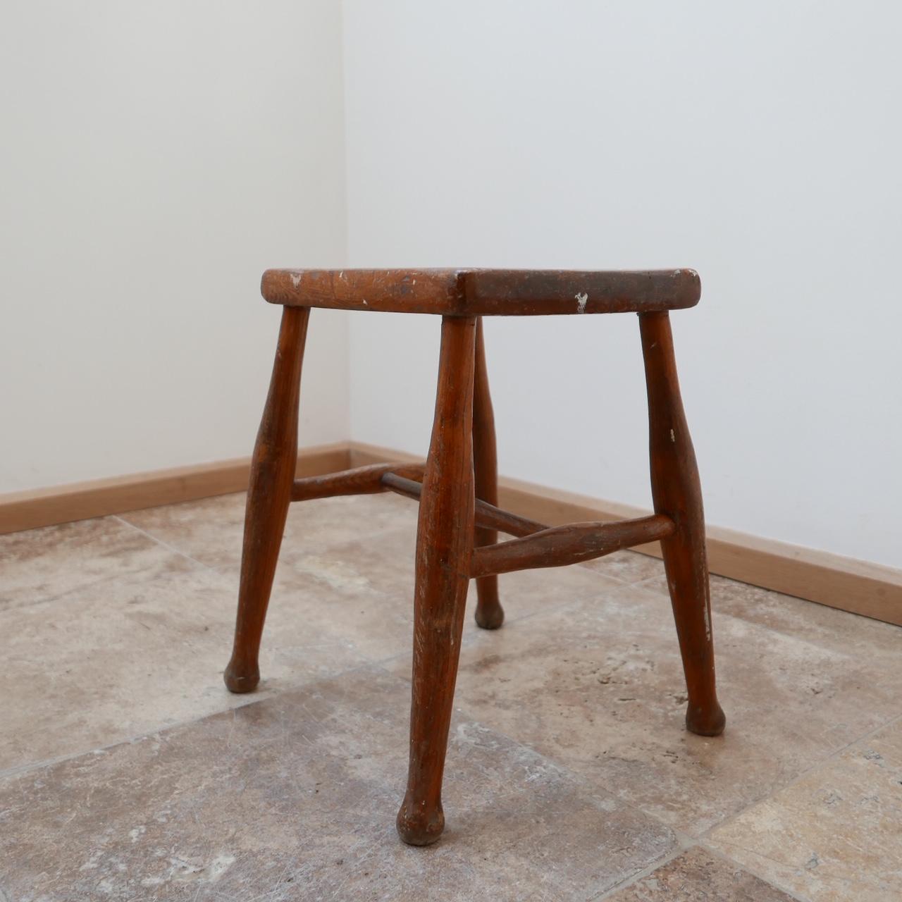 An English stool that is perfect for use as side table given the flat nature of its top.

English, circa 1950s.

Likely a milking stool used in an farm setting.

Flecks of paint and patina evidenced. It could be fully stripped if needed but we