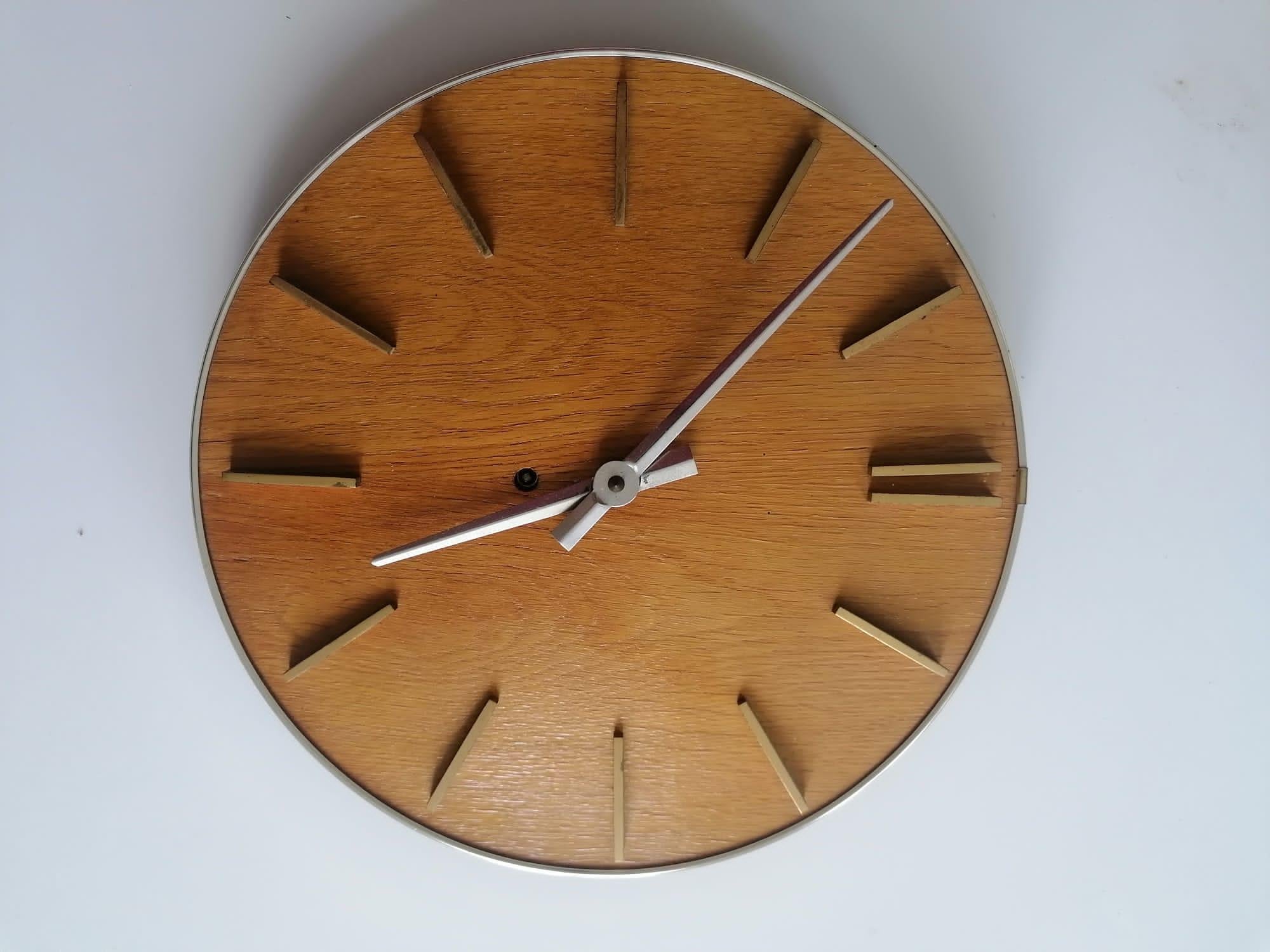 Wooden clock face and brass clock hands and index. Fitted with a battery movement. Made in Germany in the 1950s.